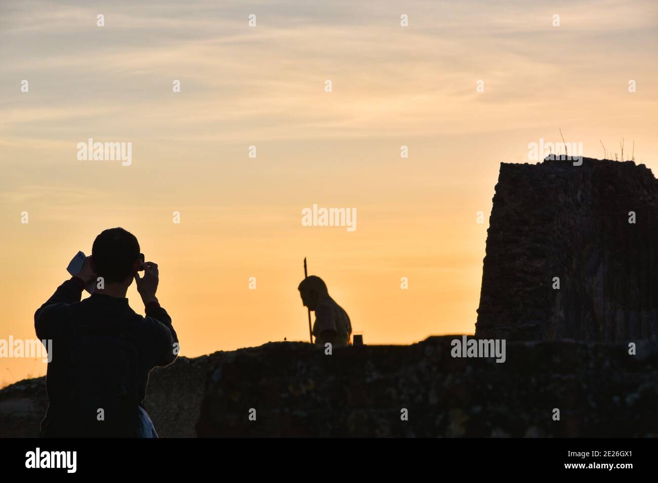 Ruinen von Pompeji. Junge Tourist mit Karte in der Hand Foto mit Smartphone von Pompeji Ruinen mit zerstörten Wand und Krieger Statue bei Sonnenuntergang. Stockfoto
