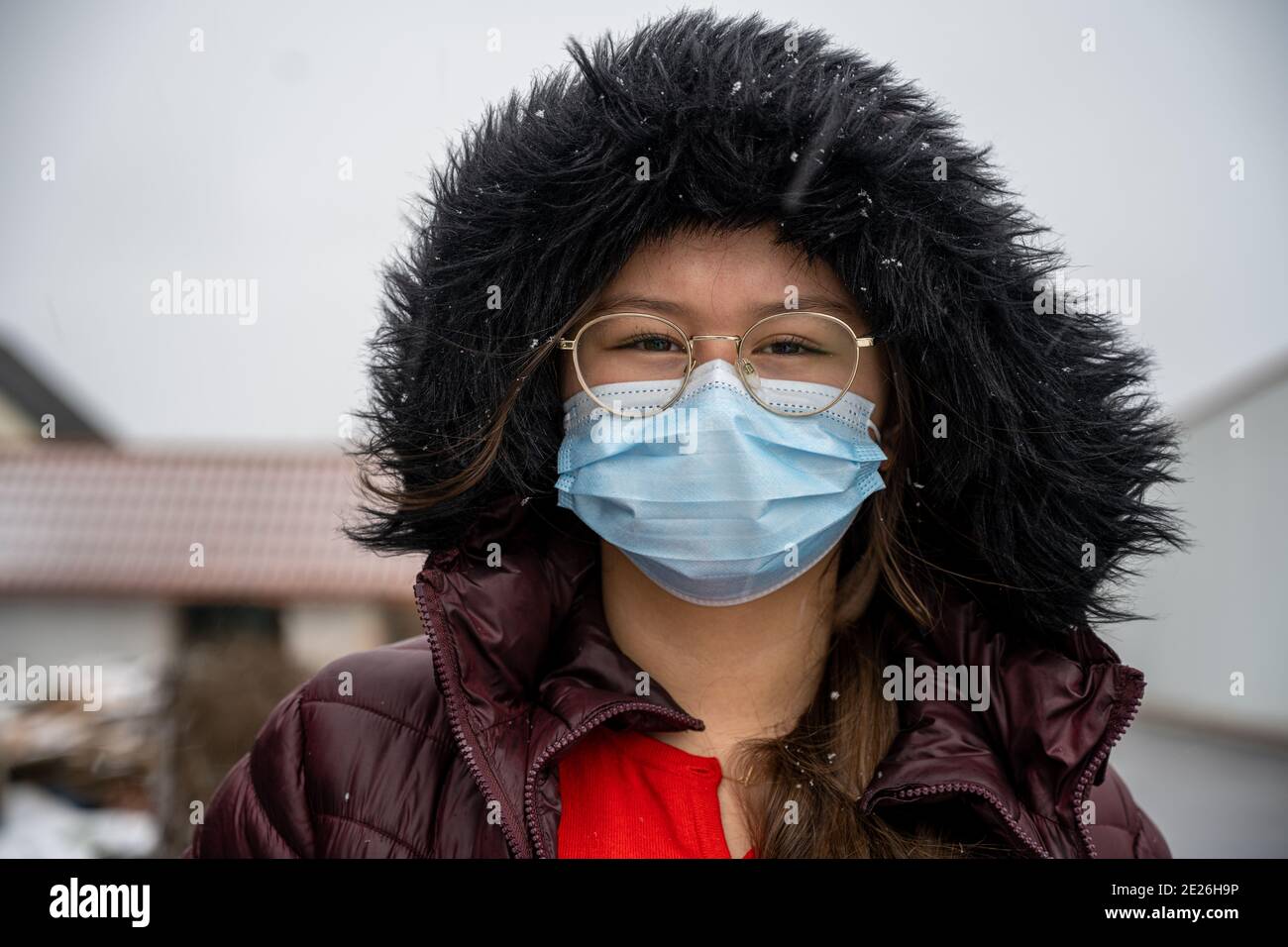 Ein Teenager-Mädchen mit in einer Winterjacke mit einer Kapuze trägt eine  schützende Gesichtsmaske. Bilder bei kalten Temperaturen und  Schneebedingungen Stockfotografie - Alamy