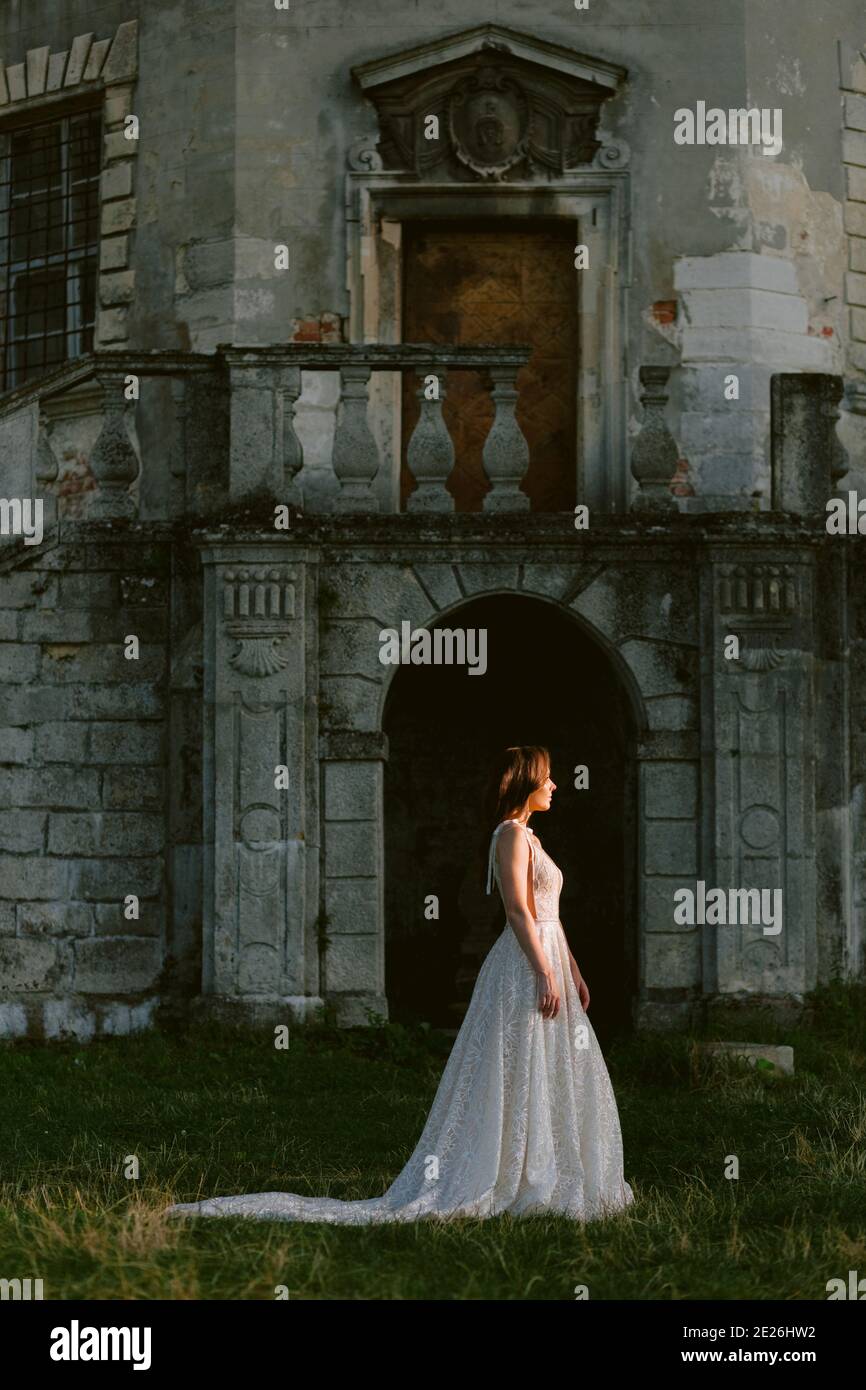 Atemberaubende Braut, die vor dem alten zerstörten Palast steht. Schöne Braut im Profil. Hochzeitsfoto Stockfoto