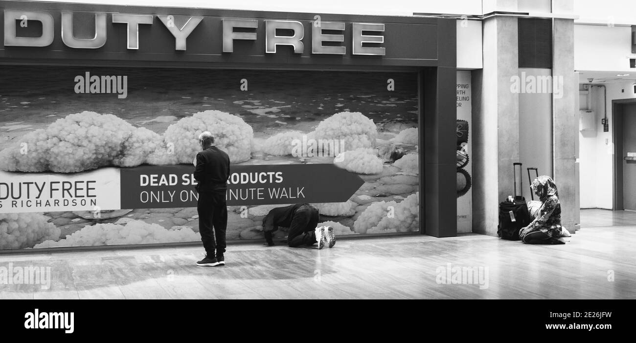 Muslimische Passagiere beten während sie auf Flüge in der Abflughalle in der Nähe von Duty Free Shops im Ben Gurion International Airport warten. Tel Aviv, Israel. Stockfoto