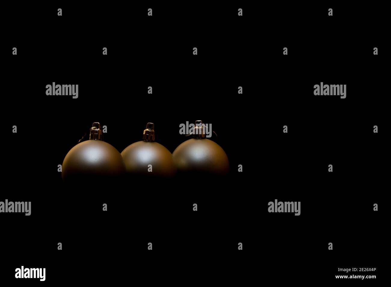 Goldene Weihnachtsdekorationen auf schwarzem Hintergrund. Drei Weihnachtskugeln Stockfoto