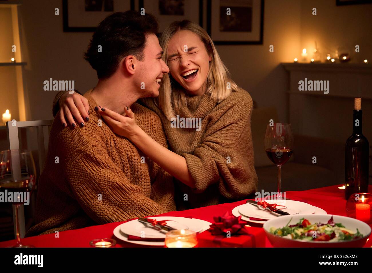 Glückliches junges Paar umarmt lachend feiert Valentinstag zusammen zu Hause. Stockfoto