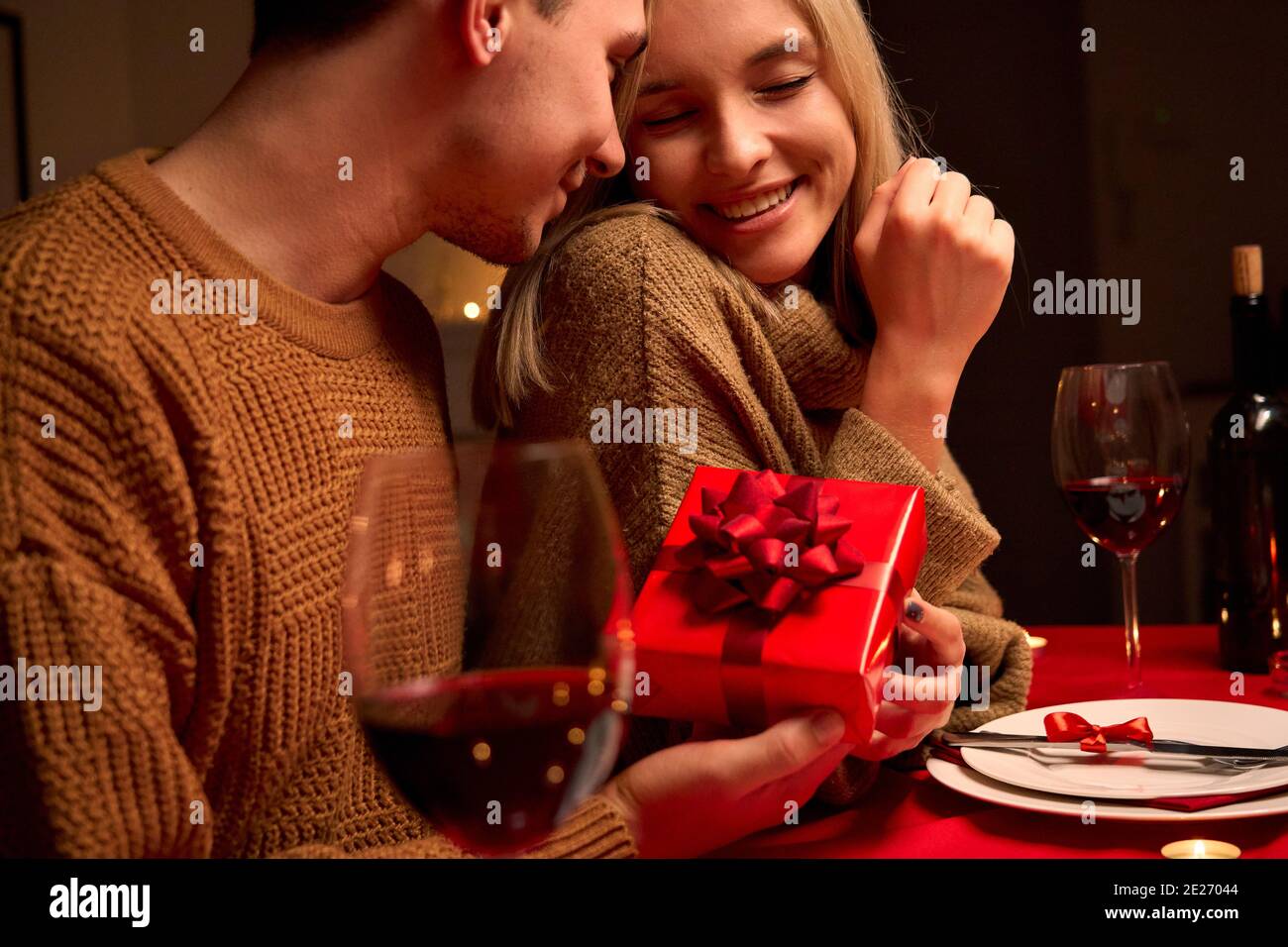 Liebevoller Mann geben rote Geschenkbox Umarmung geliebte Frau oder Valentinstag. Stockfoto