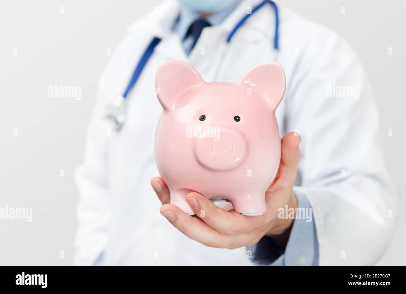 Arzt hält Sparschwein. Gesundheitskosten, Krankenversicherungskonzept Stockfoto