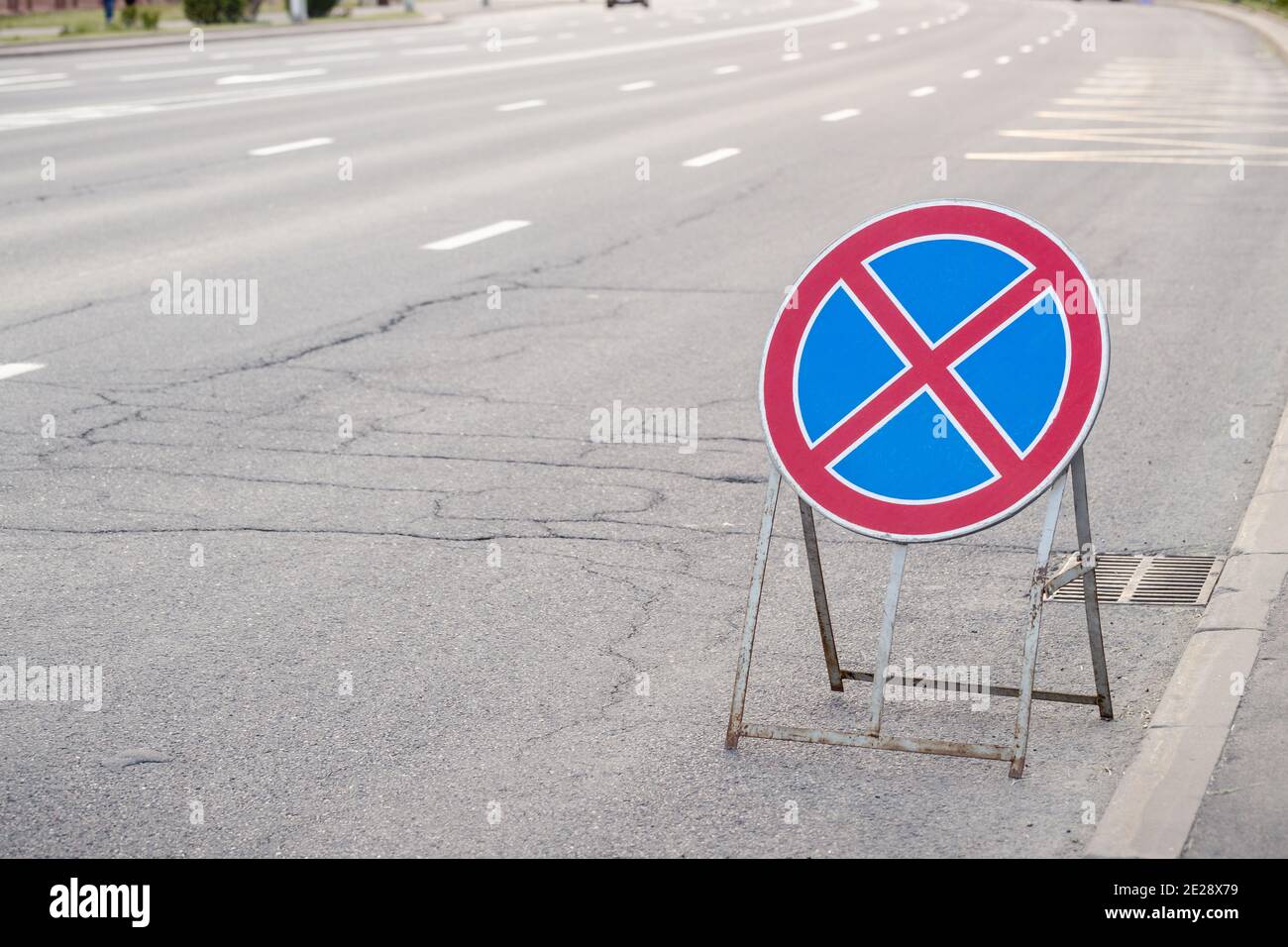 Rundes rotes Kreuz auf blauem Hintergrund Zeichen gegen geknackten Asphalt  Hintergrund. Verkehrszeichen, das bedeutet, dass es nicht erlaubt ist,  Fahrzeuge hier zu parken Stockfotografie - Alamy