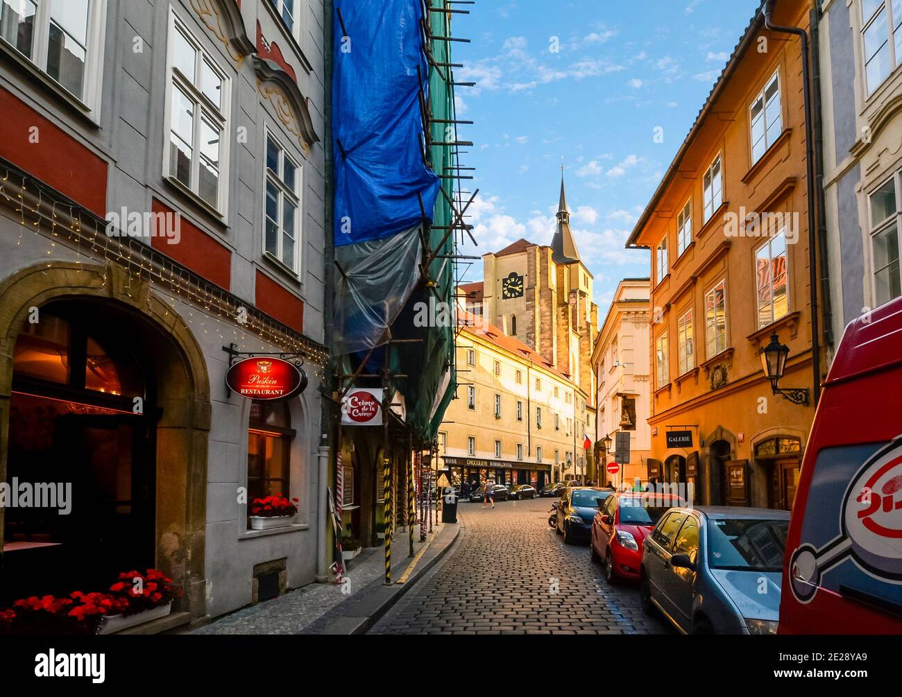 Eine schmale gepflasterte Straße mit Restaurant und Bauzone in der Kleinseite der Mala Strana in Prag, Tschechien. Stockfoto