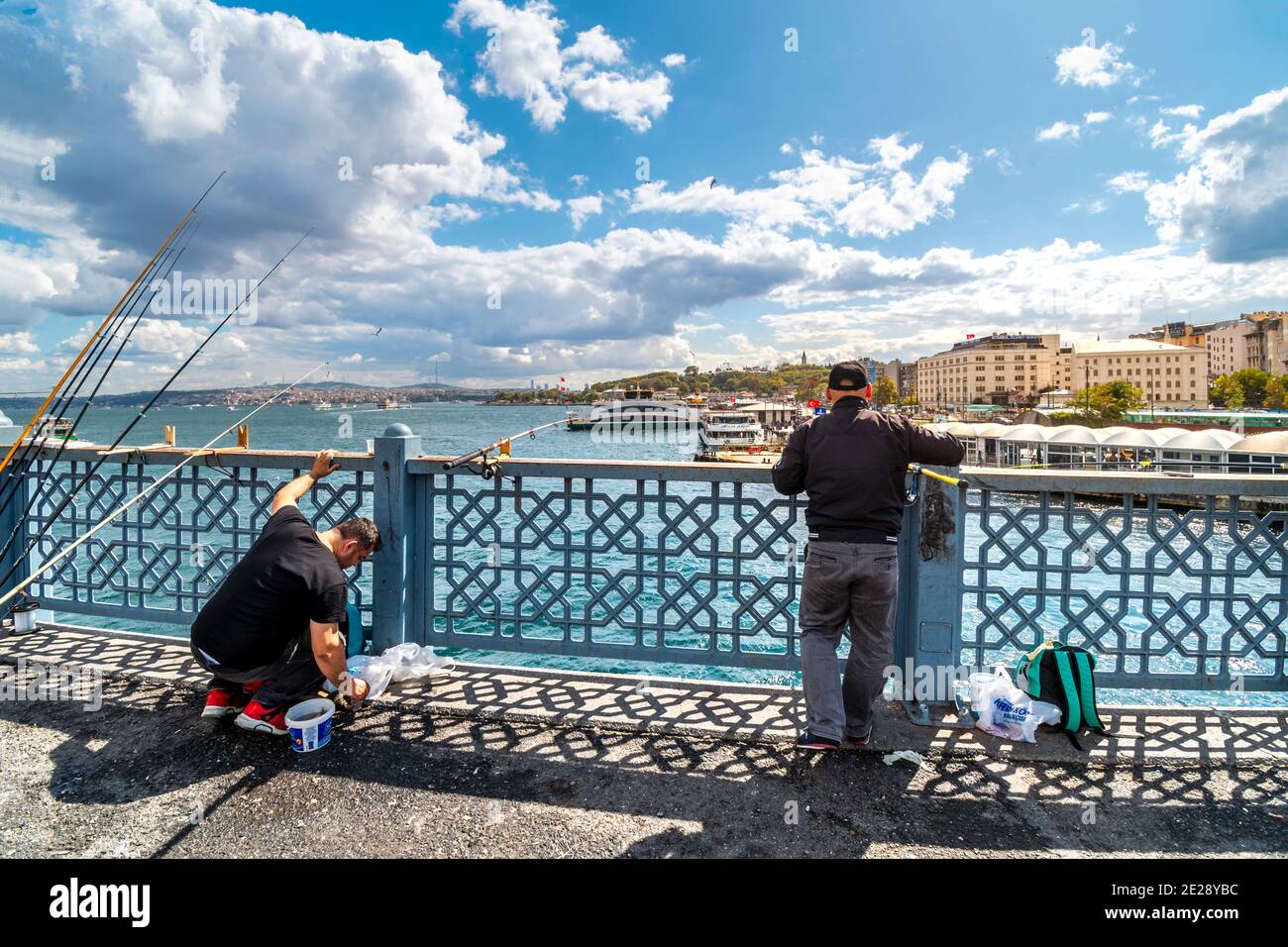 Lokale türkische Fischer hängen ihre Angelruten an der Galata-Brücke, mit dem Sultanahmet-Viertel in der Ferne. Stockfoto
