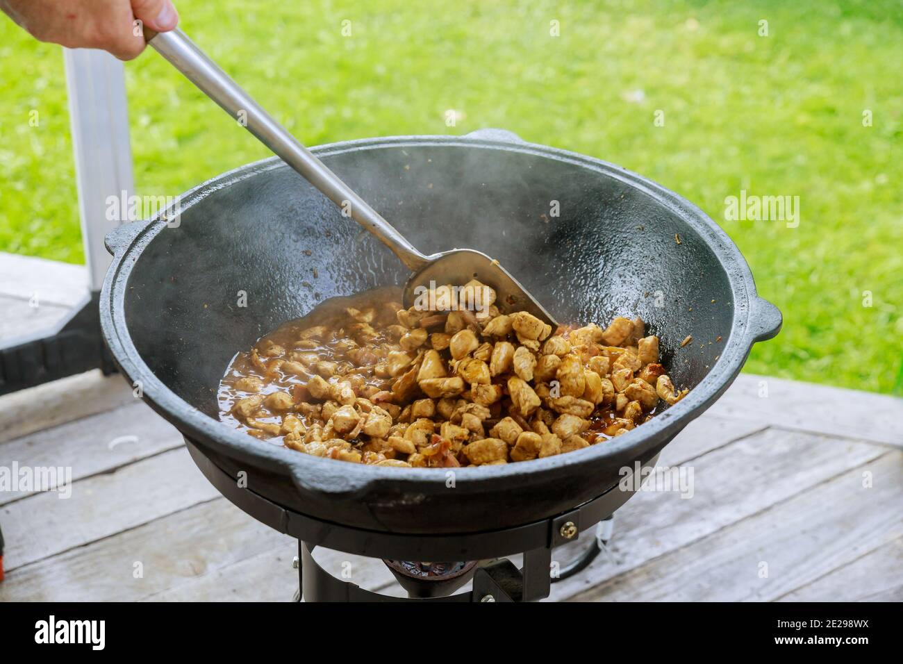 Prozess des Kochgulasch in Eisenkessel im Freien. Das Fleisch wird gebraten. Stockfoto