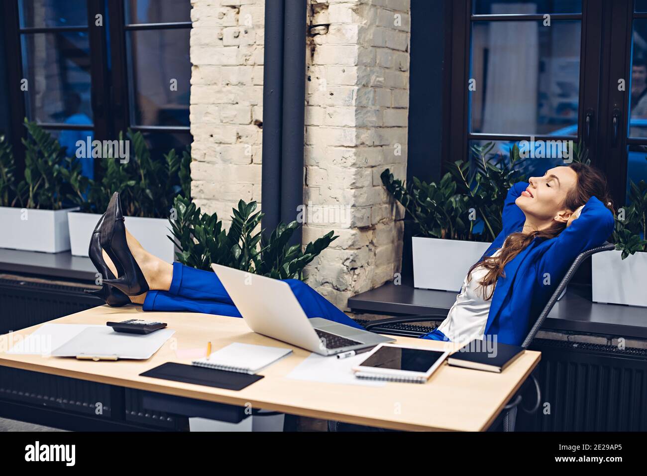 Geschäftsfrau, die sich im Büro auf einem Stuhl entspannt Stockfoto