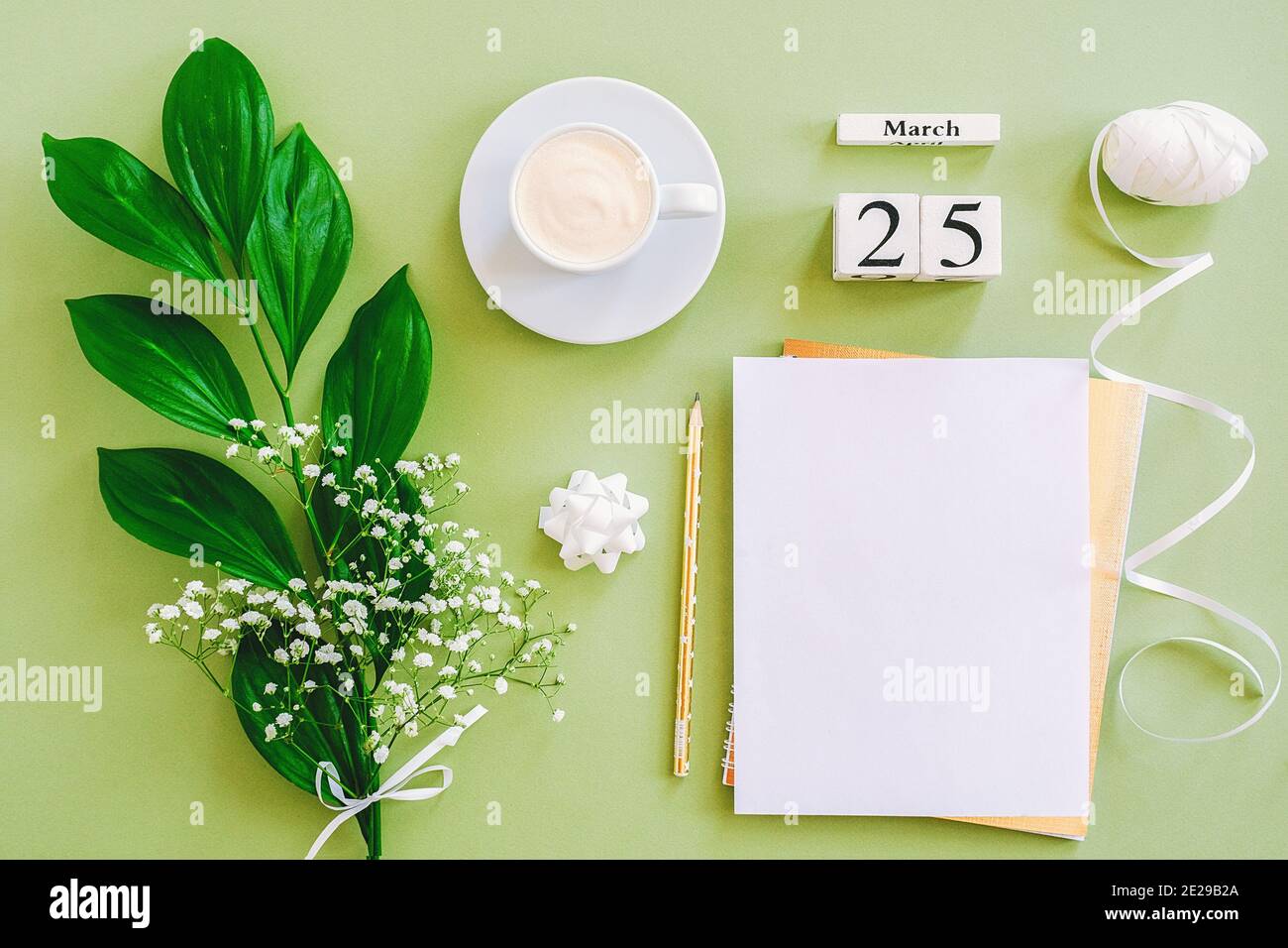 Holzwürfel Kalender März 25. Notizblock, Tasse Kaffee, Blumenstrauß auf grünem Hintergrund. Konzept hallo Frühjahr Creative Draufsicht Flat Lay Mock up. Stockfoto