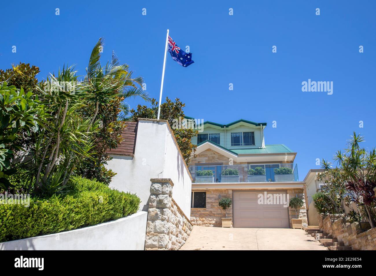 Sydney Küste freistehendes Haus in Avalon Beach mit üppigem Garten Und die australische Flagge, die auf der Fahnenstange, Sydney, Australien, fliegt Stockfoto