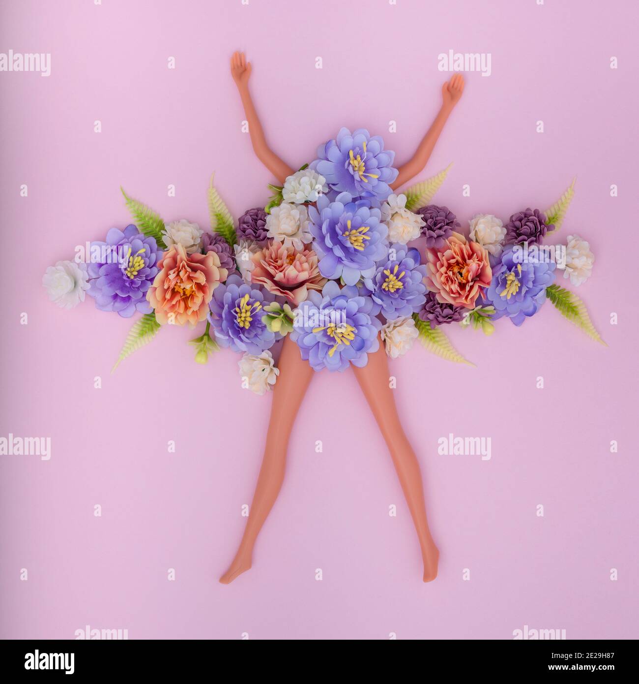 Schlanke Puppe Beine und Hände mit künstlichen Blumen auf rosa Hintergrund Stockfoto