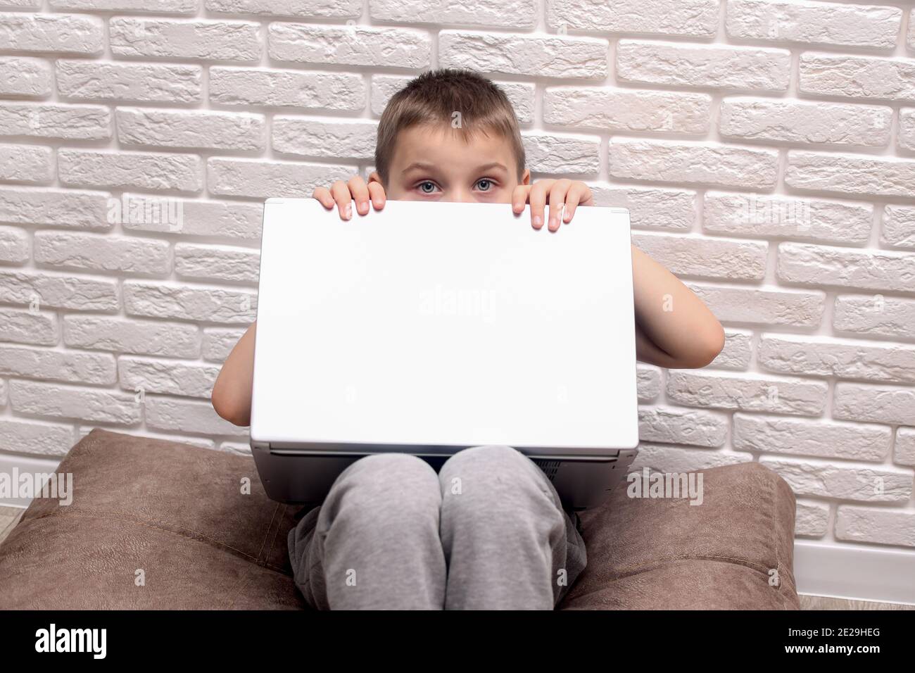 Ein Junge sitzt vor einem Laptop und schaut von hinten heraus. Stockfoto