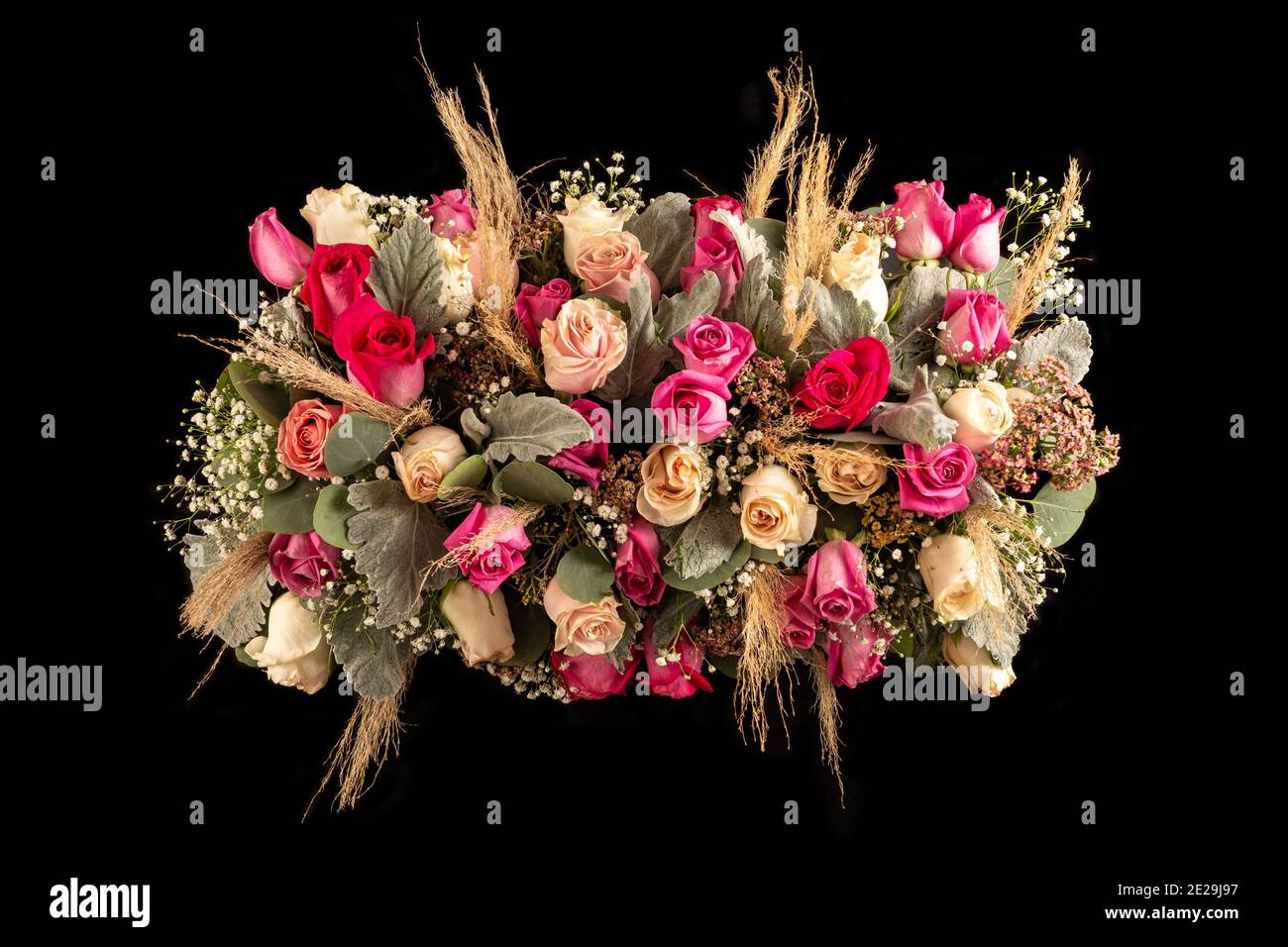 Arrangement Blumentisch Mittelpunkt mit rosa Tönen Rosen und Laub. Isoliert auf schwarzem Hintergrund Stockfoto