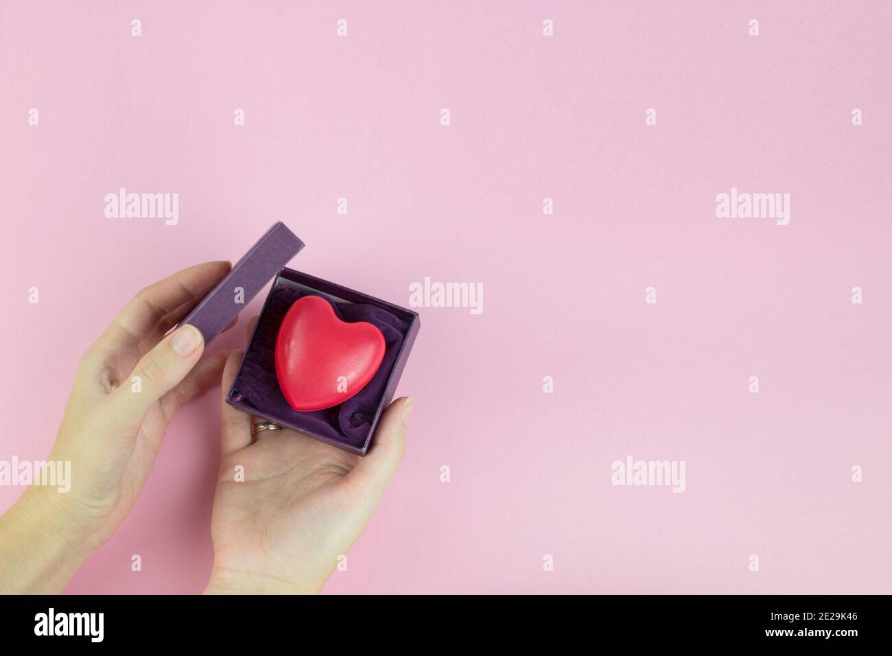 Valentinstag Hintergrund mit Frau Hand, Geschenkbox und rotem Herz. Draufsicht. Flach liegend Stockfoto
