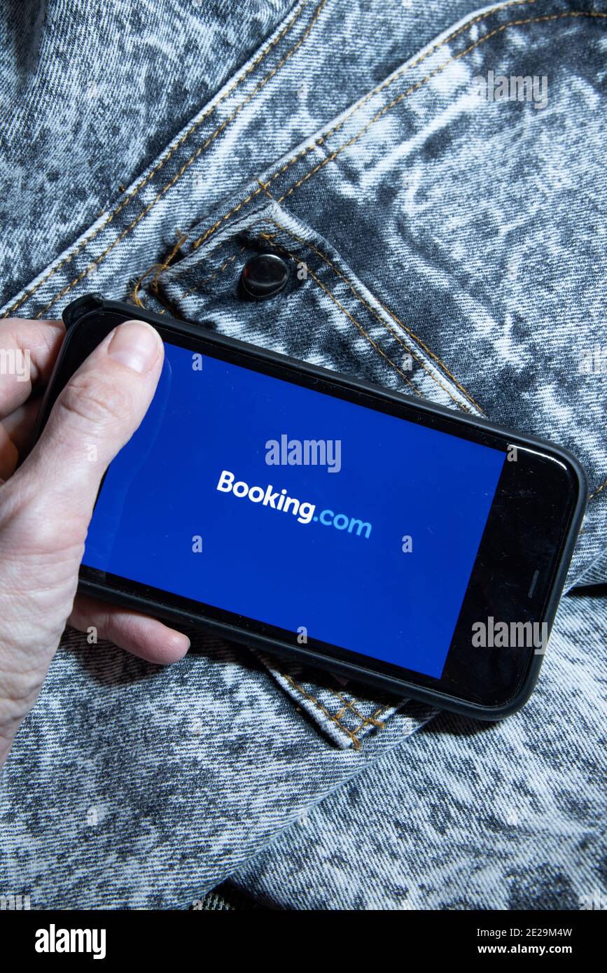 Hände halten iPhone 11 mit App von booking.com Service. Smartphone-, Reise- und Hotelindustrie-Krise aufgrund von Covid- oder Coronavirus-Pandemie. Stockfoto