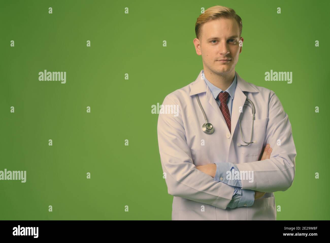 Junge gutaussehende Mann Arzt mit blonden Haaren vor grünem Hintergrund  Stockfotografie - Alamy