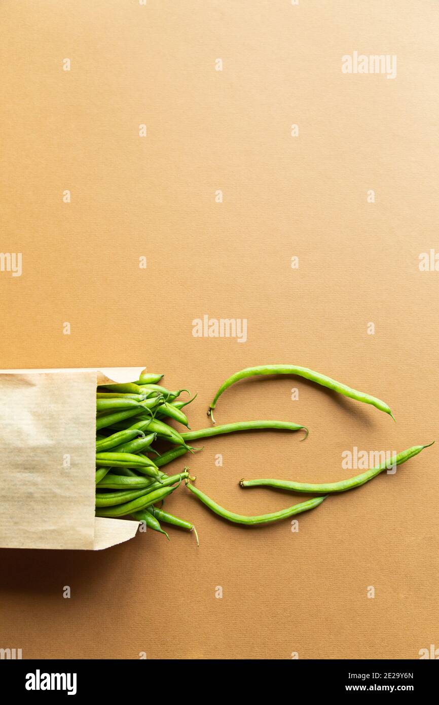 Grüne Bohnen oder Kidney Beans in einem Bastelsack auf braunem Hintergrund. Ernten Sie gesunde Bio-Lebensmittel Stockfoto