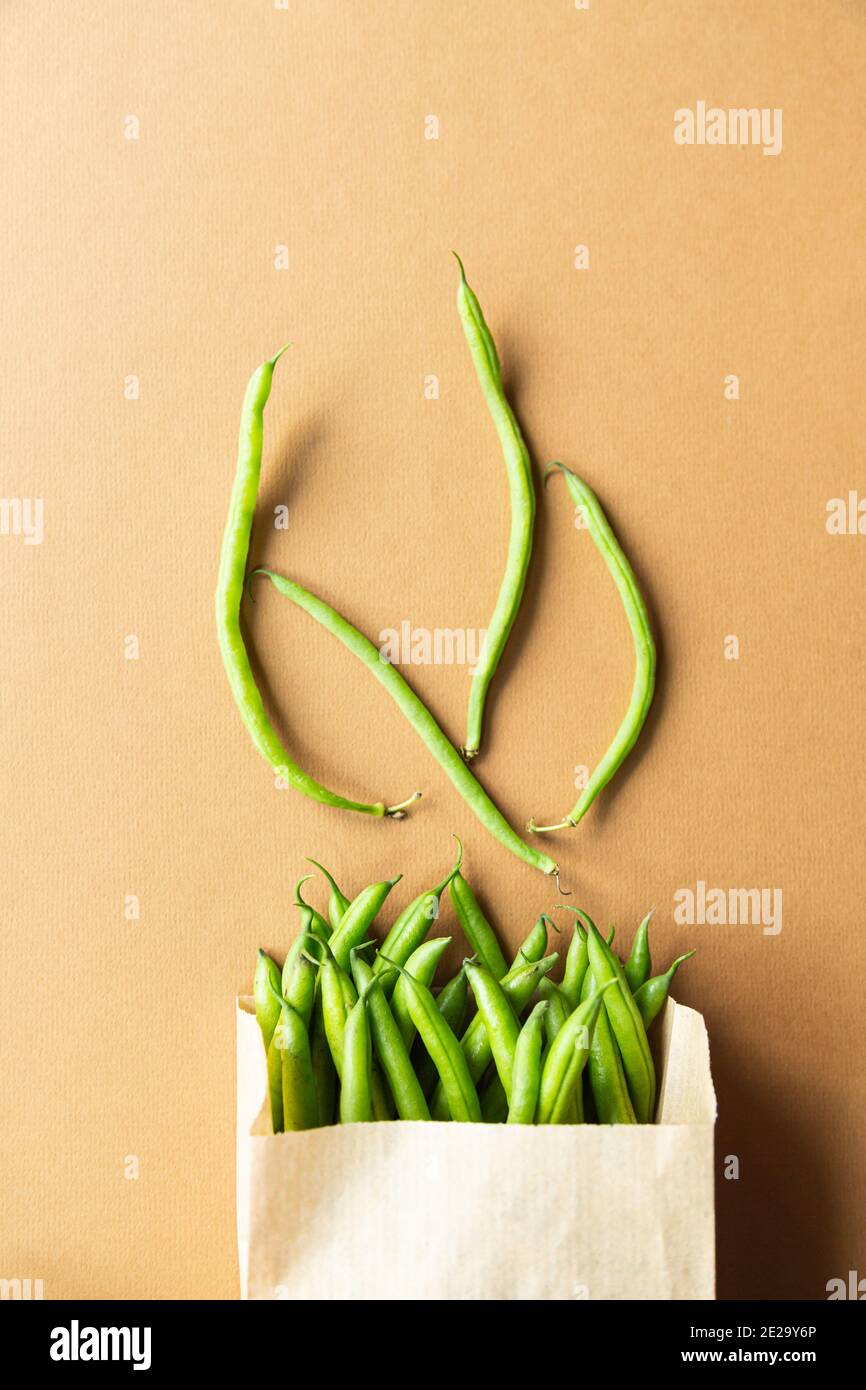 Grüne Bohnen oder Kidney Beans in einem Bastelsack auf braunem Hintergrund. Ernten Sie gesunde Bio-Lebensmittel Stockfoto