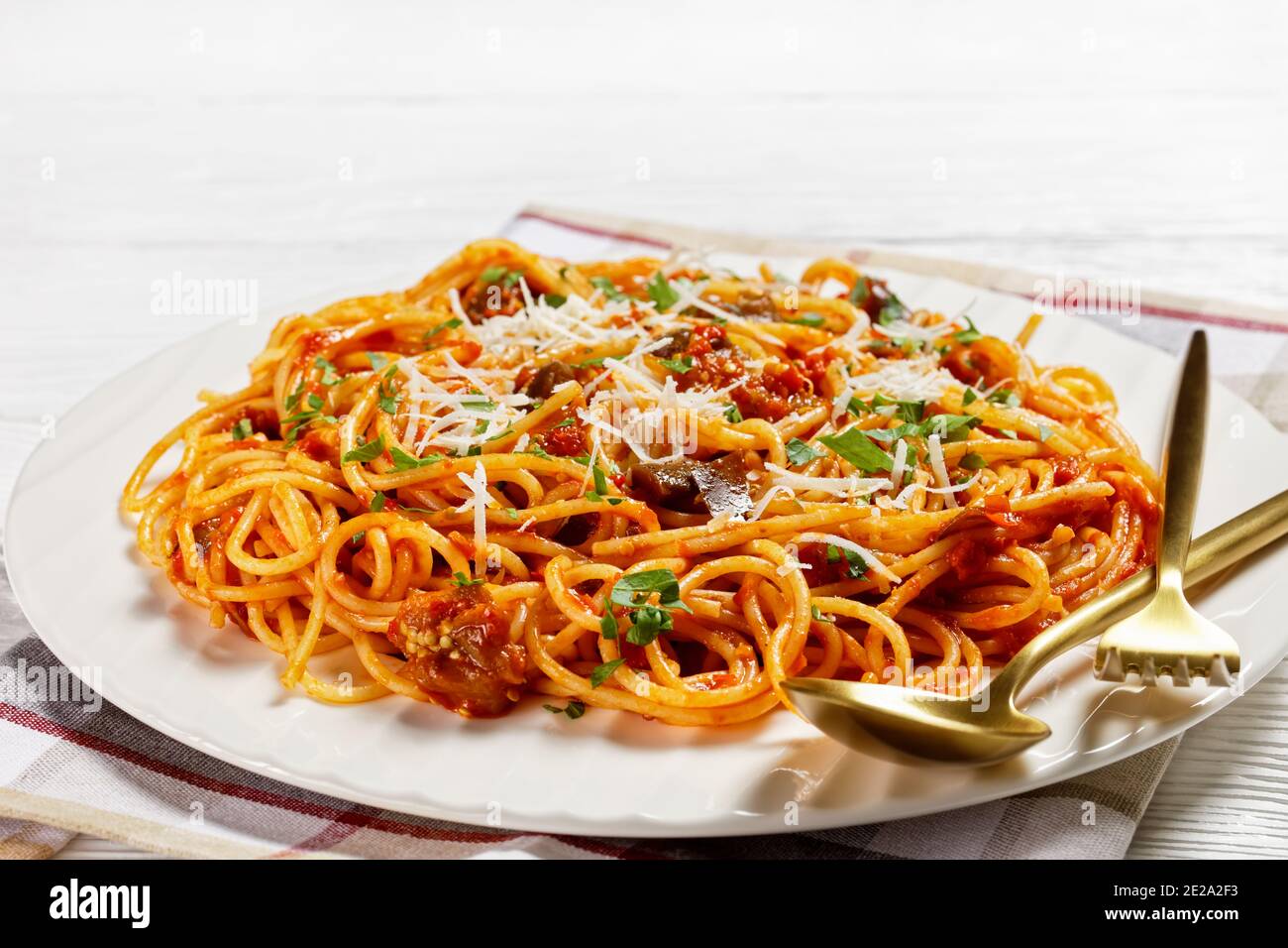 Classicl sizilianische Pasta Gericht sautierten Auberginen mit Tomatensauce geworfen und gekrönt mit zerfetzten Parmesan auf einem weißen Teller serviert, italienische Küche, Stockfoto