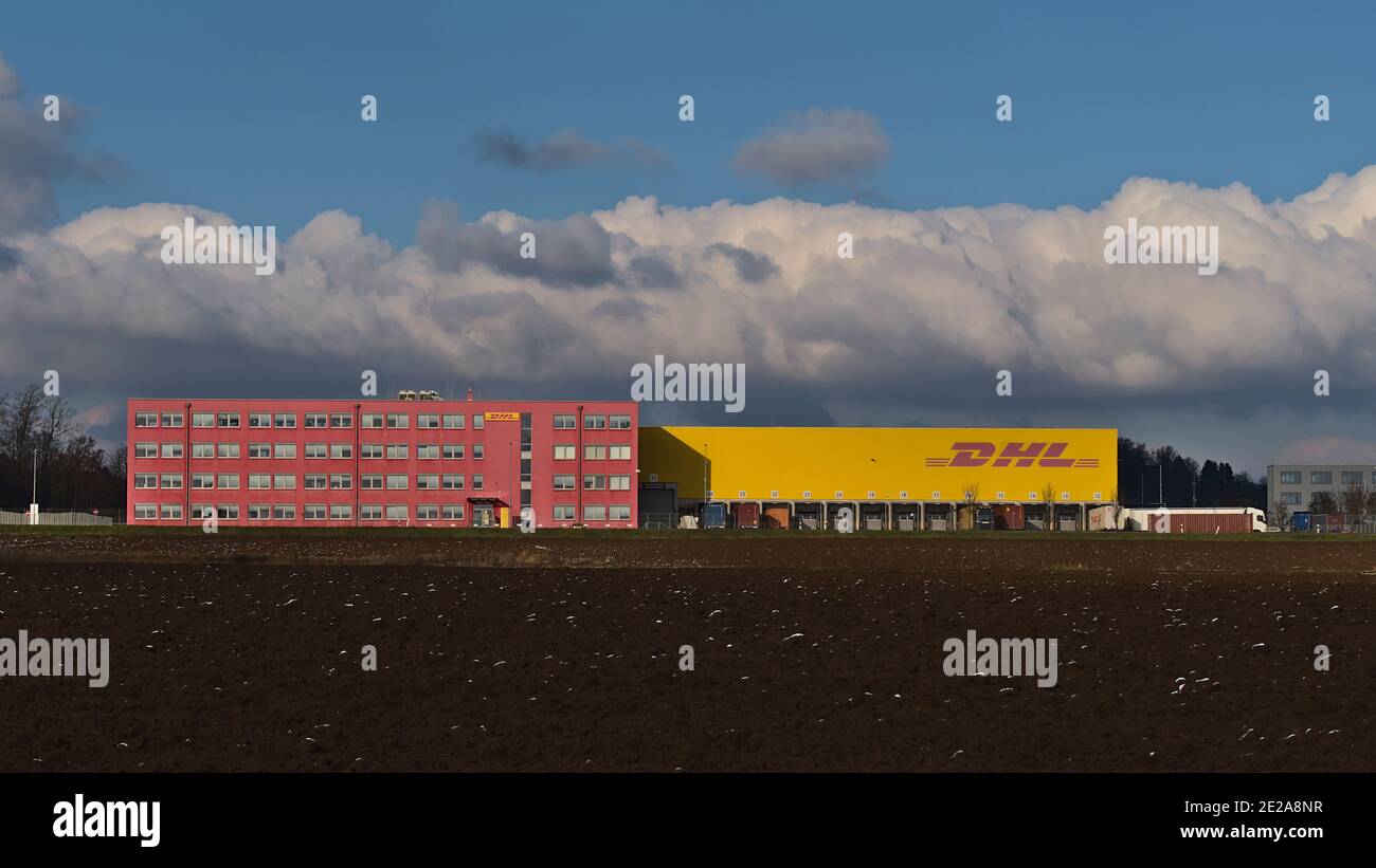 Vorderansicht des pinkfarbenen und gelben Logistikzentrums des Transportunternehmens DHL Global Forwarding, das zur Deutsche Post DHL Group gehört, mit Business-Logo. Stockfoto