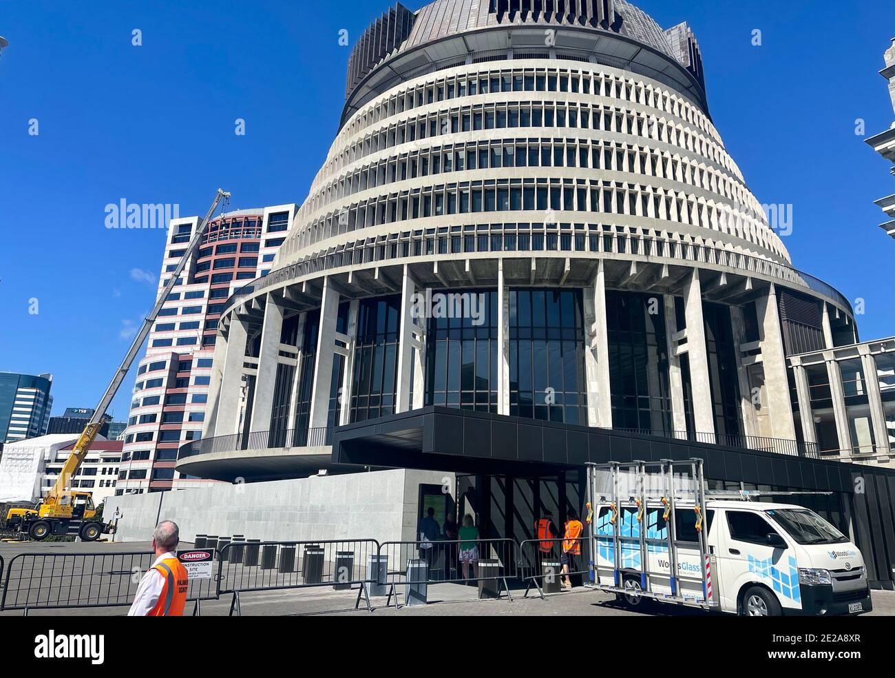 Wellington, Neuseeland. Januar 2021. Arbeiter reparieren den kaputten Haupteingang des neuseeländischen Parlaments in Beehive, Wellington, Neuseeland, 13. Januar 2021. Die neuseeländische Polizei verhaftete einen 31-jährigen Mann, nachdem er am Mittwochmorgen einen Axt-Angriff auf das Parlament gestartet hatte. Die Motivation für den Angriff ist nicht klar, und der Mann wurde mit vorsätzlichem Schaden und Besitz einer Angriffswaffe angeklagt, berichteten lokale Medien. Quelle: Meng Tao/Xinhua/Alamy Live News Stockfoto