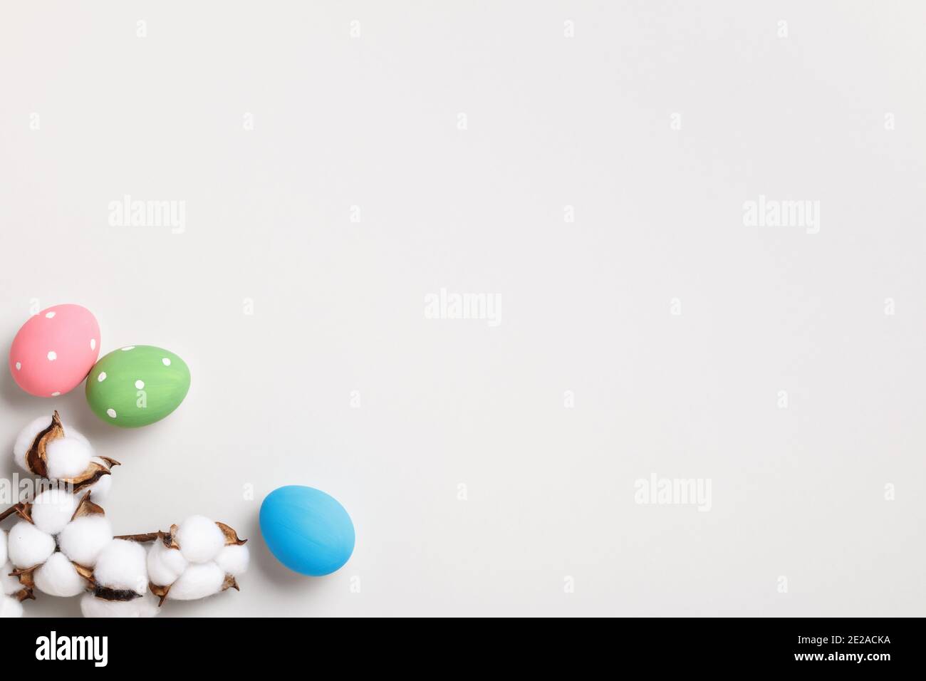 Frohe Ostern. Bunte Eier und ein Zweig aus Baumwolle auf grauem Hintergrund. Flache Grußkarte mit Platz zum Kopieren. Stockfoto