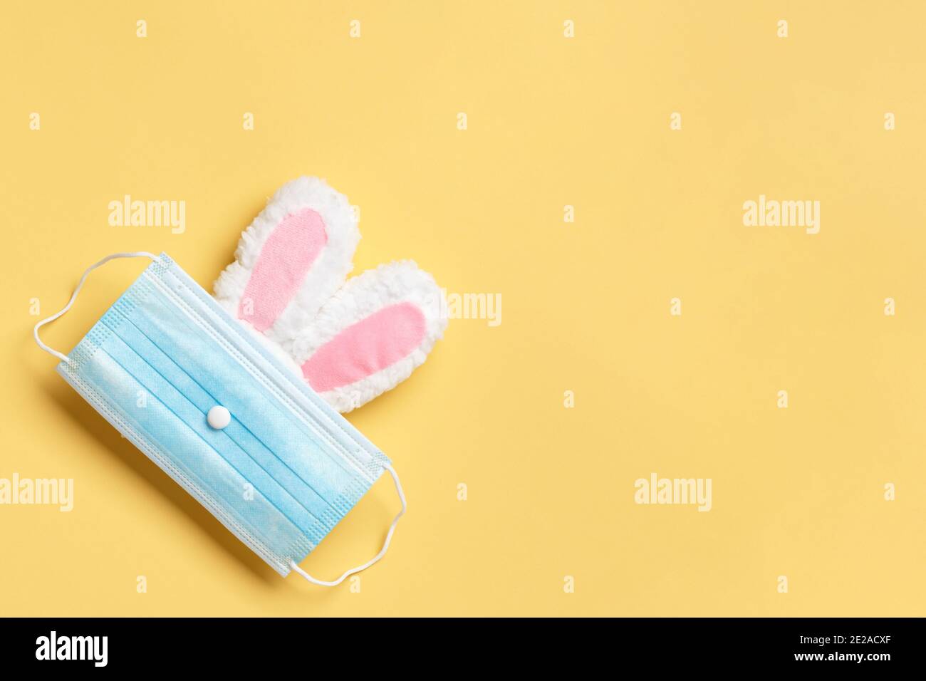 Ostern und Quarantäne. Kaninchen in einer schützenden medizinischen Maske auf gelbem Hintergrund. Stockfoto