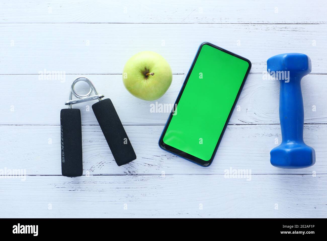 Smartphone mit Sportausrüstung auf weißem Holzhintergrund Stockfoto