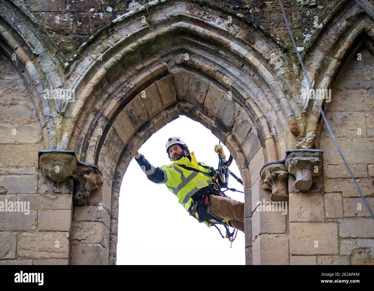 Der Steinmetz James Preston von SSH Conservation, abseils von Rievaulx Abbey in North Yorkshire als English Heritage bereitet sich auf die Durchführung von lebenswichtigen Naturschutzarbeiten vor. English Heritage beauftragt eine Untersuchung der Abtei Rievaulx in einem fünfjährigen Zyklus, um den Zustand der Abtei vom Boden bis zur Spitze der Struktur zu beurteilen. Stockfoto