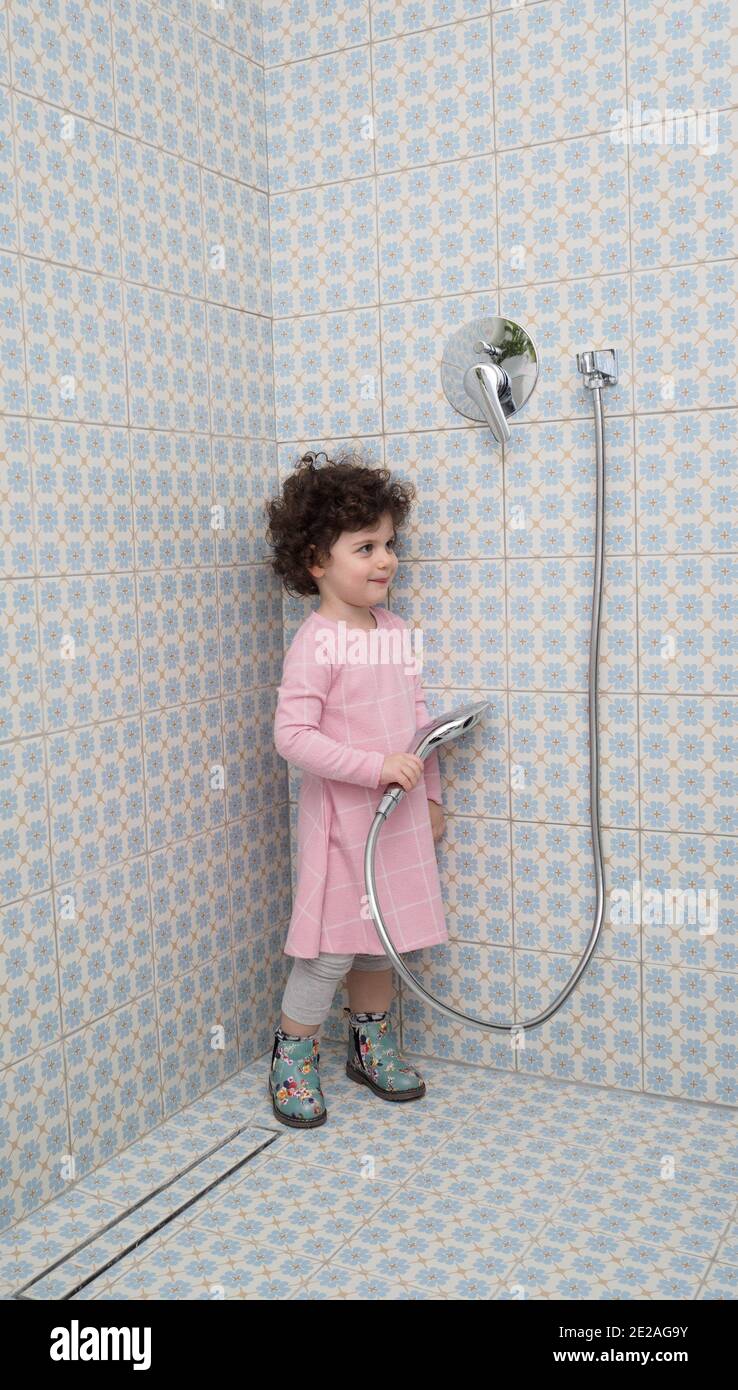 Voll gekleidet, spielt Kleinkind Mädchen in der Dusche Stockfoto
