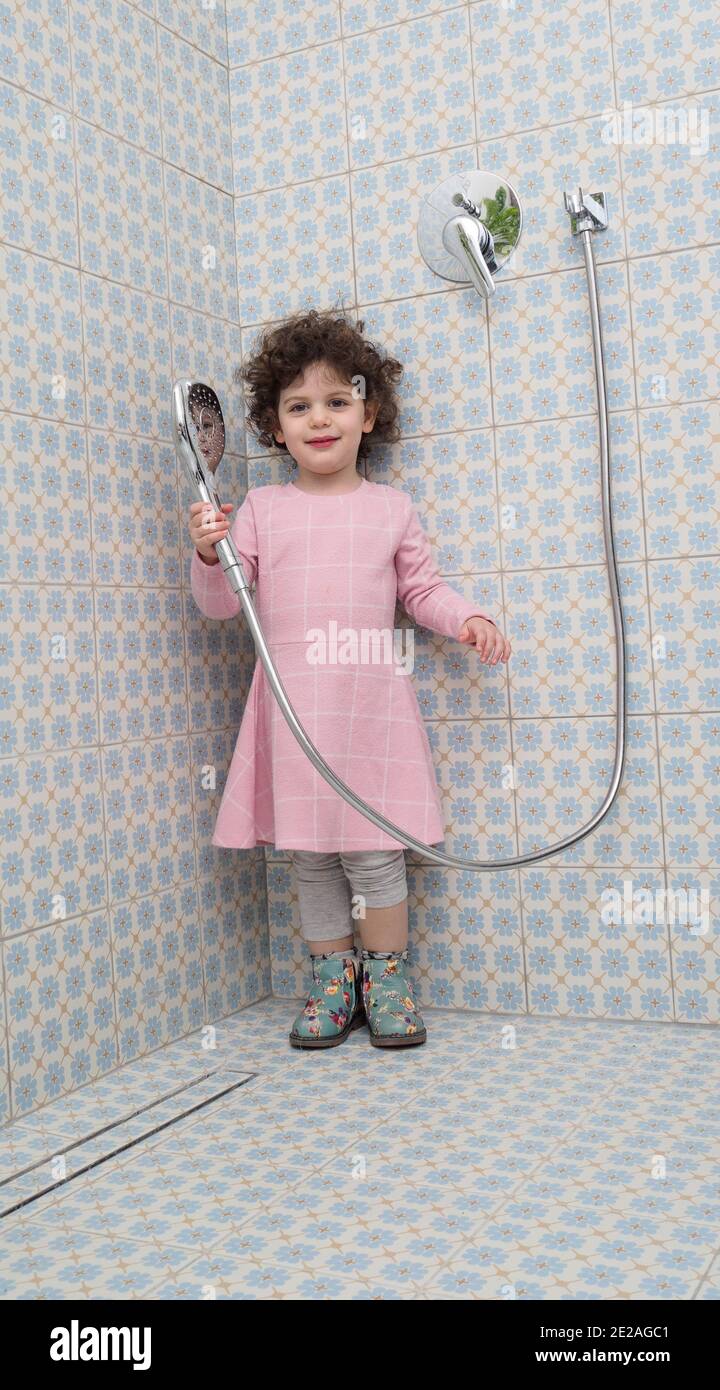 Voll gekleidet, spielt Kleinkind Mädchen in der Dusche Stockfoto
