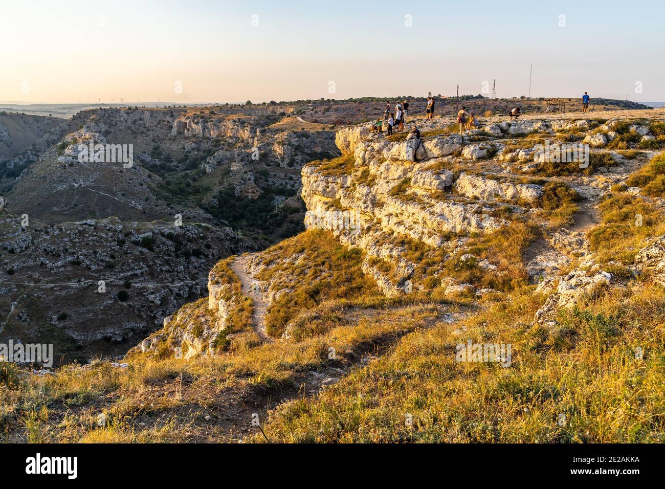 Menschen genießen den Sonnenuntergang im Belvedere Murgia Timone mit Blick auf den Fluss Gravina in der Nähe von Matera, Basilicata, Italien Stockfoto