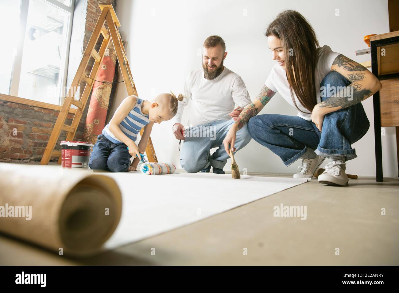 Junges Paar, Familie tun Wohnung Reparatur zusammen selbst. Mutter, Vater und Sohn tun zu Hause Verjüngungskur oder Renovierung. Konzept der Beziehungen, Bewegung, Liebe. Kleben Tapete vor dem Aufhängen Stockfoto