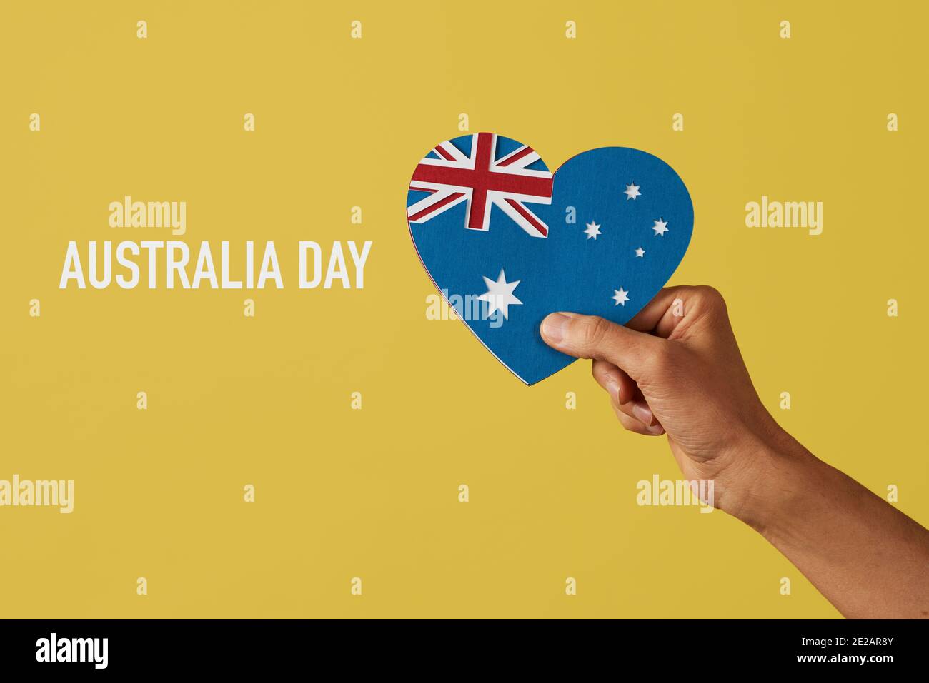Nahaufnahme der Hand eines Mannes, der eine australische Flagge in Form eines Herzens hält, mit Ausschnitten aus Papier in verschiedenen Farben und dem Text australi Stockfoto