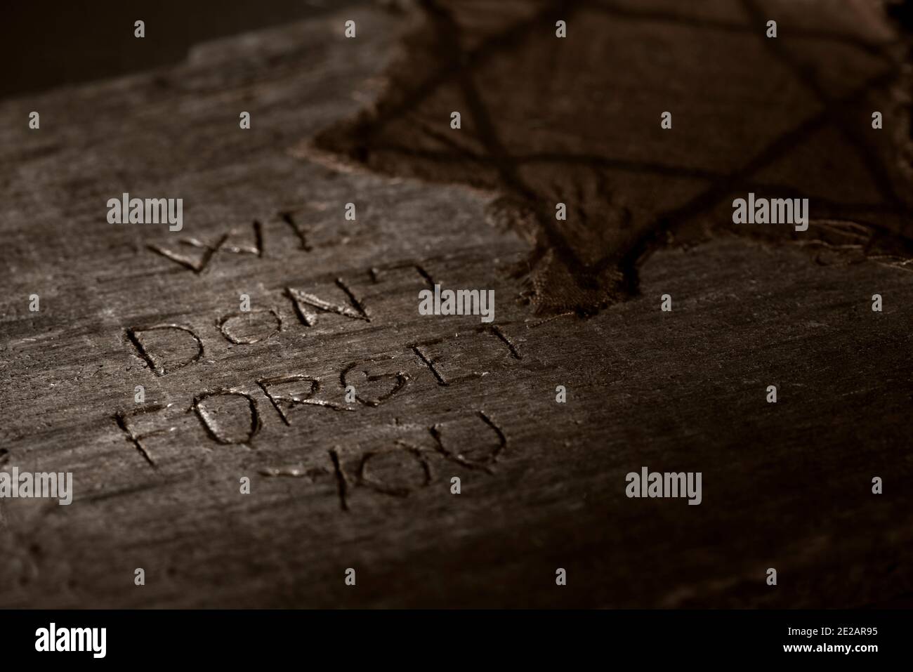 Nahaufnahme eines zerlumpten jüdischen Abzeichen auf einem dunklen rustikalen Holzfläche mit dem Text vergessen wir Sie nicht Darin geschnitzt Stockfoto