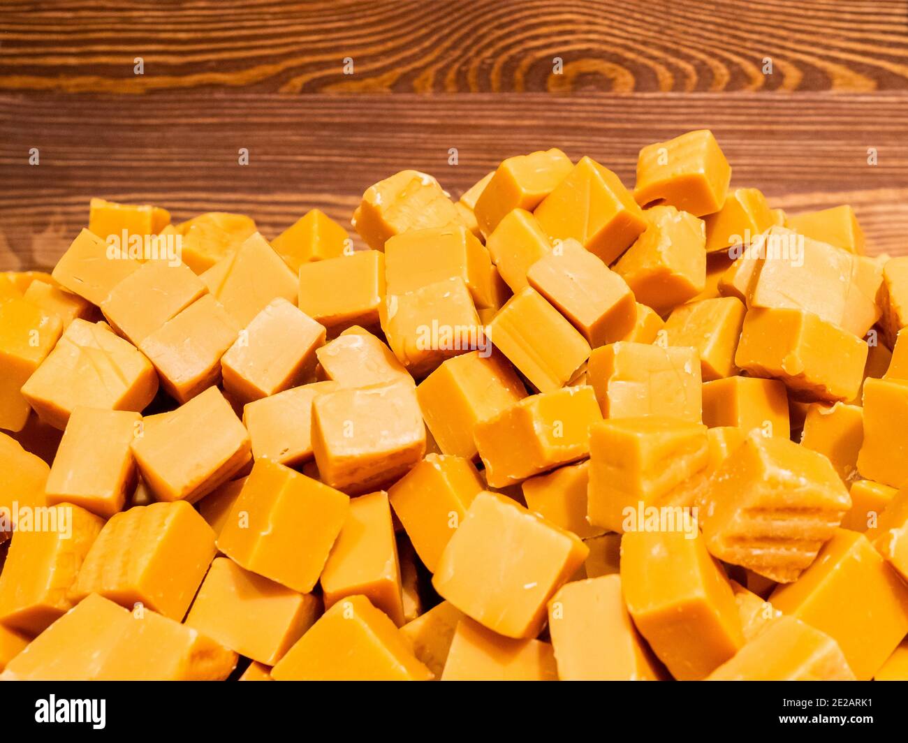 Ein Haufen Toffee Bonbons in Orange in Form von Würfeln. Abstrakter Hintergrund köstlicher Goodies. Stockfoto