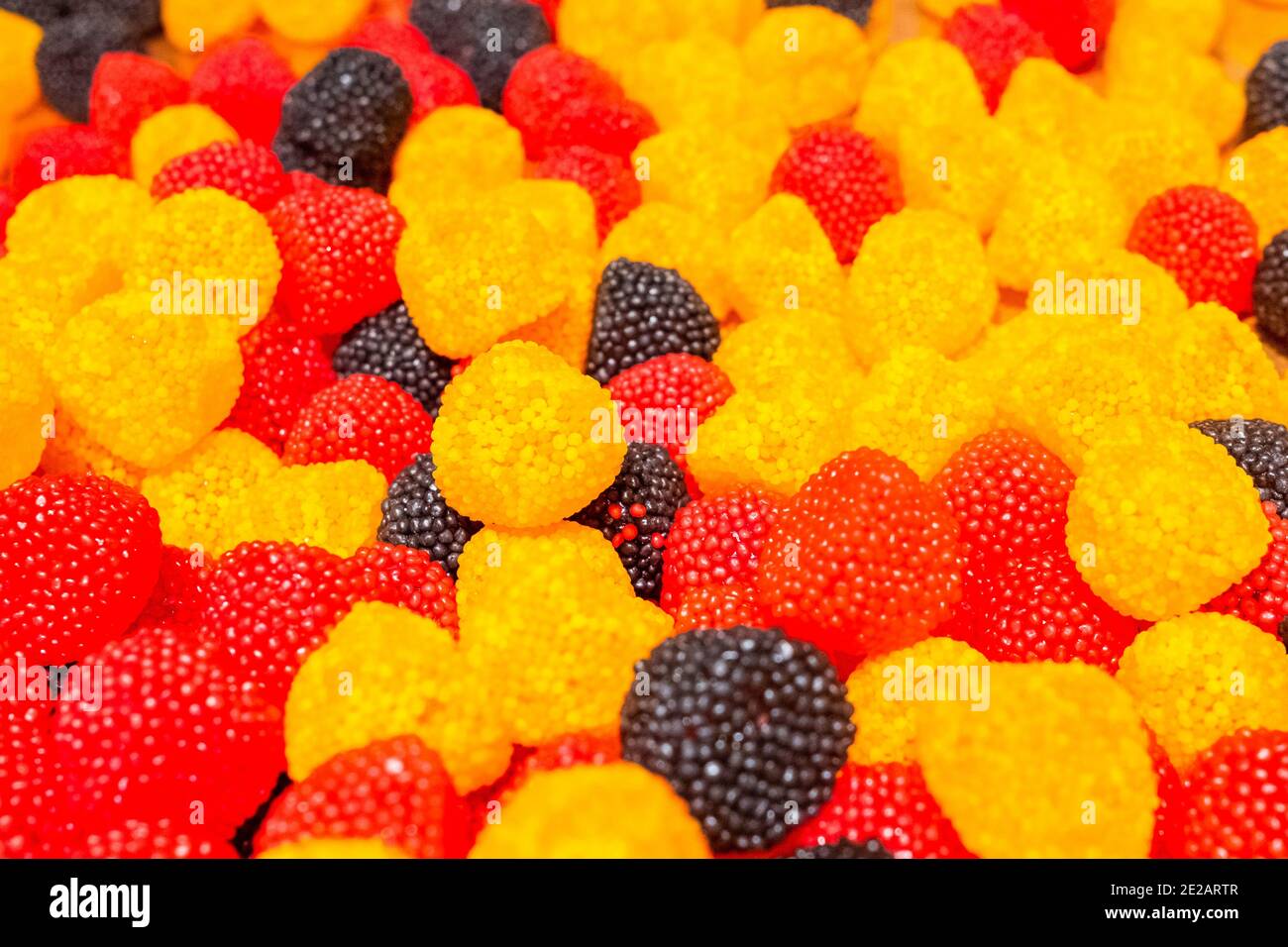Leuchtend gelbe, schwarze und rote Marmelade, die Süßigkeiten in Form von  Beeren kaut. Süße schöne Delikatesse aus Gel Fruchtsäften. Farbenfroh  Stockfotografie - Alamy