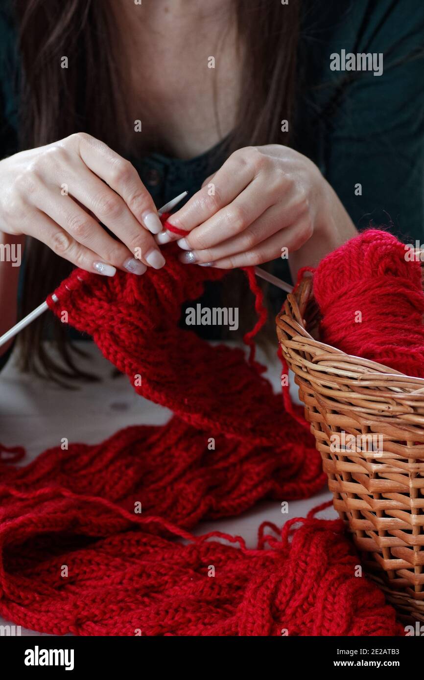 Junge Frau strickt roten Schalldämpfer zu Hause in der Freizeit, Fancywork und Nadelarbeit Design, Nahaufnahme der Handarbeit, Kopierraum, Home Freizeit Konzept Stockfoto