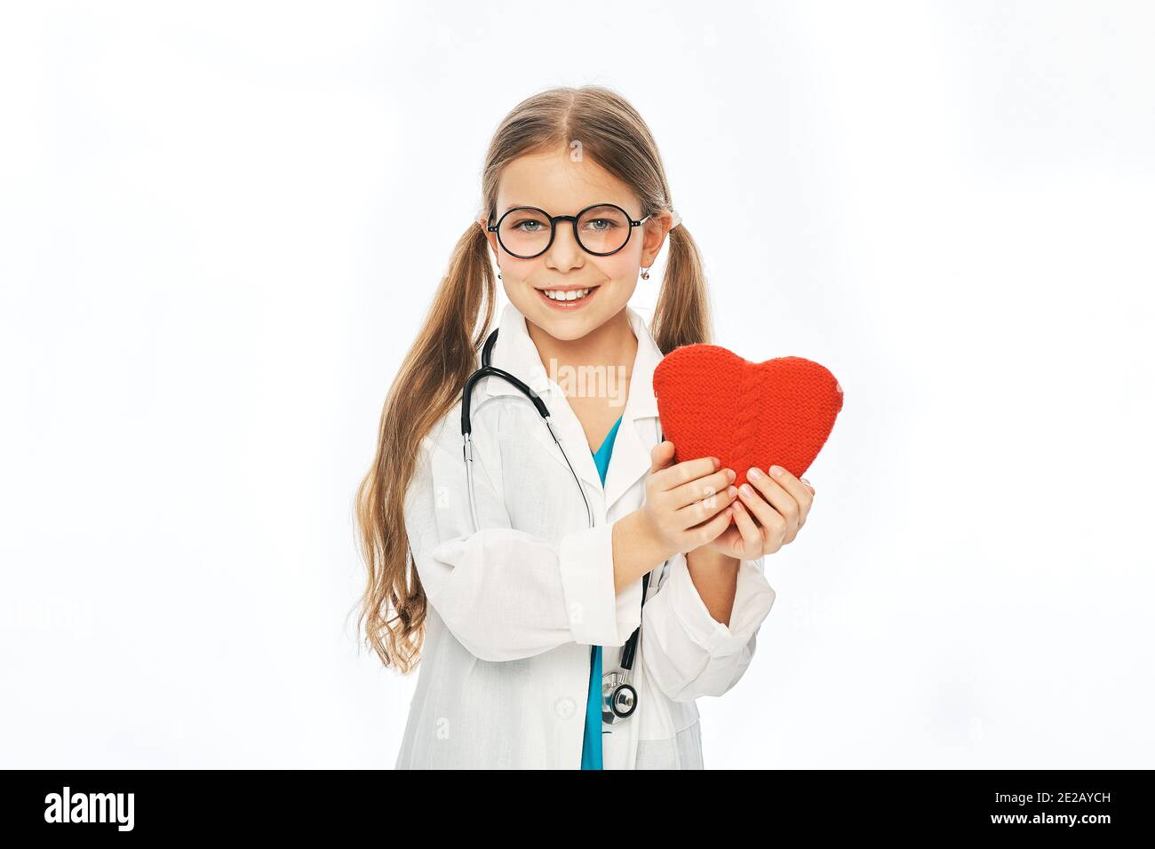 Kleines Mädchen mit Brille und medizinischem Mantel, das Herzform hält. Medizinische Betreuung und Betreuung von Kindern, Pädiatrie Stockfoto