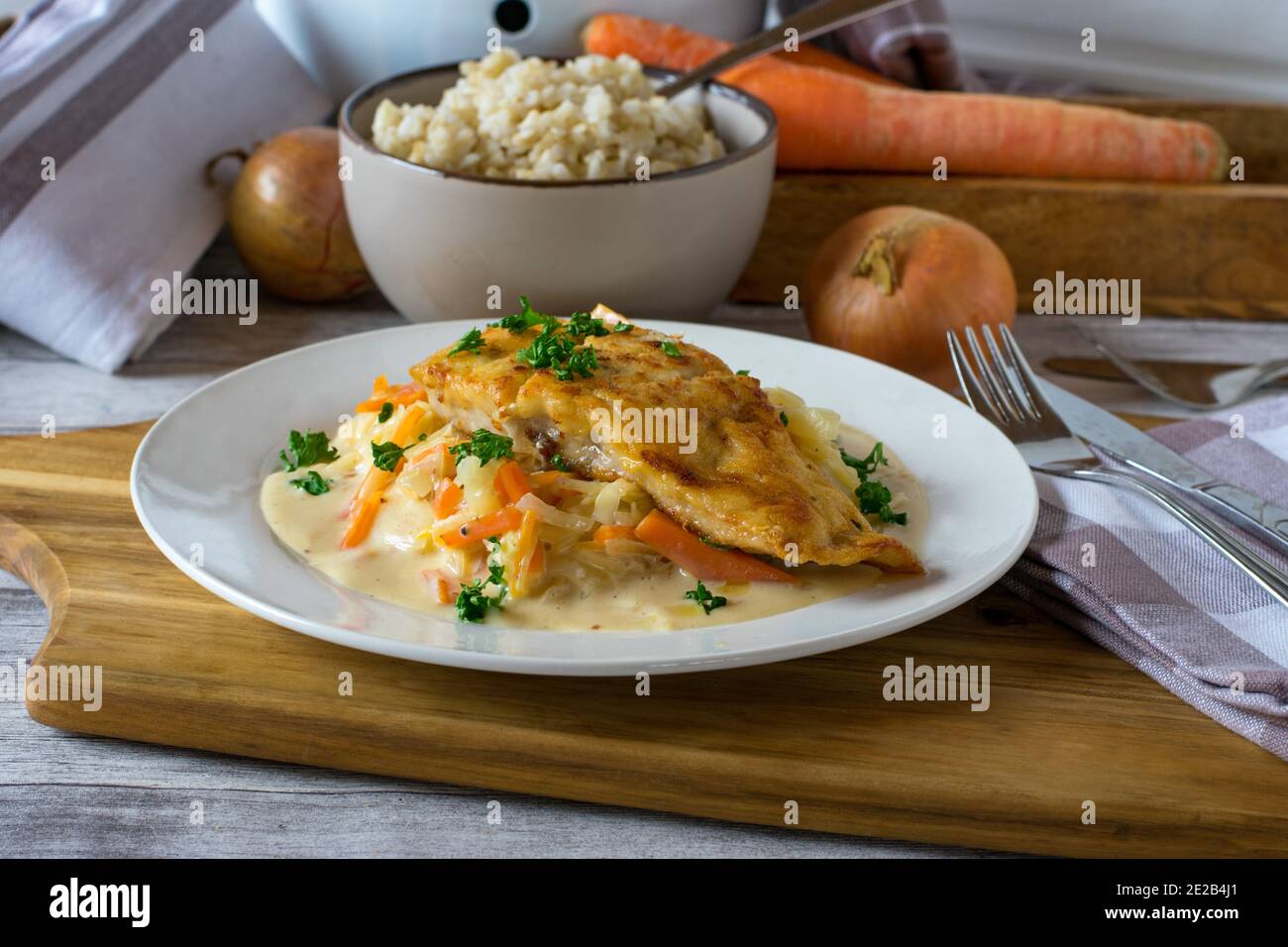 Fischfilet mit Gemüse und braunem Reis auf einem Teller Stockfoto