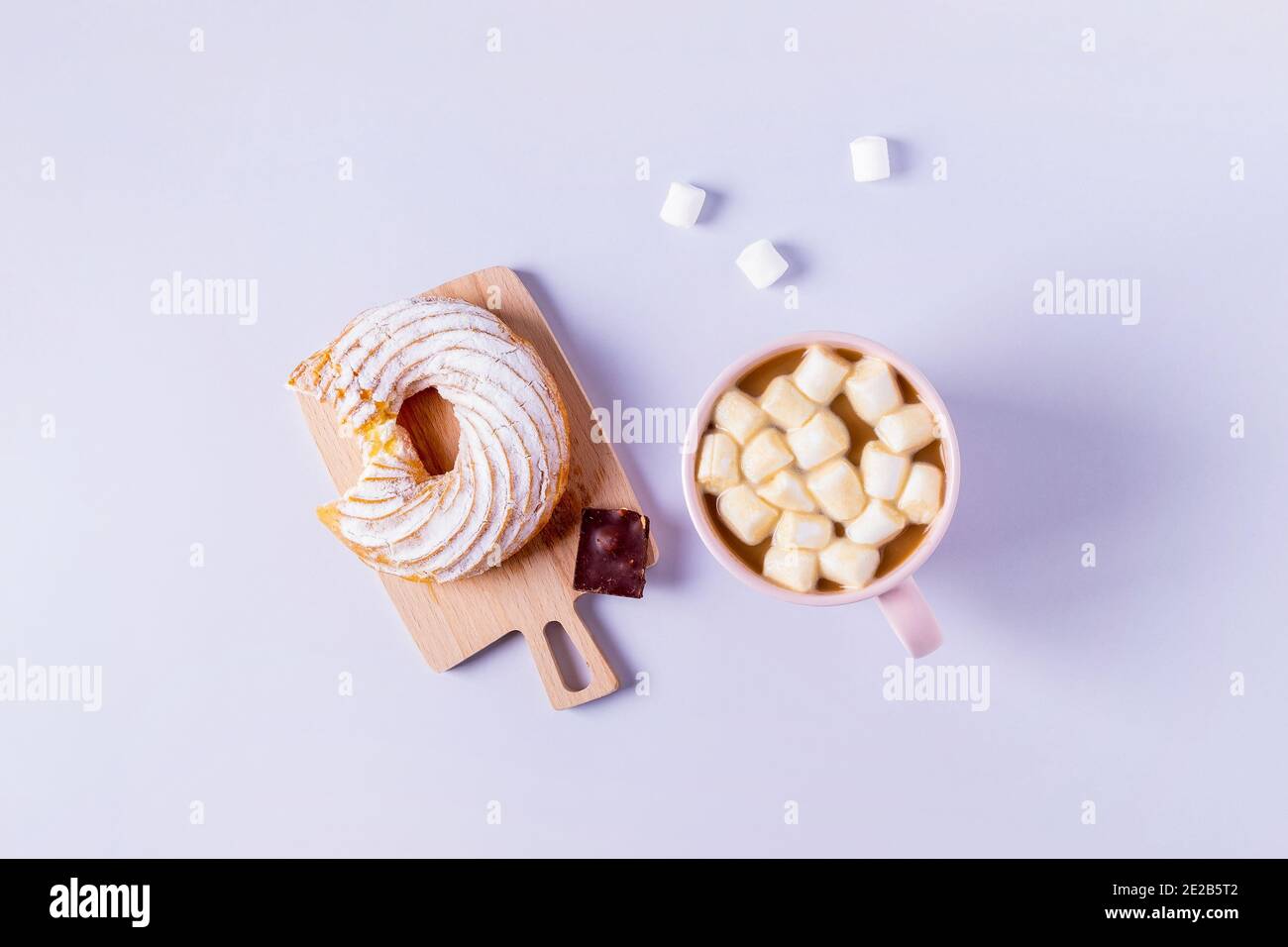 Draufsicht auf Stillleben eines gebissenen Kuchens auf einem kleinen Servierbrett und einer Tasse Kakao mit Marshmallows. Selektiver Fokus, horizontale Ausrichtung. Stockfoto