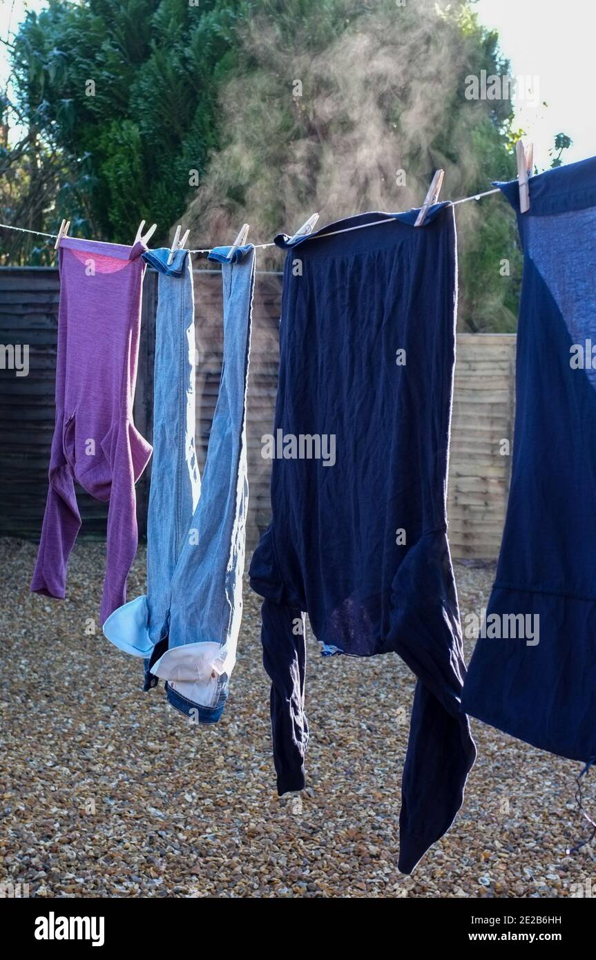 Frisch gewaschene Kleidung dampft an einem sehr kalten Tag in der Sonne. Stockfoto