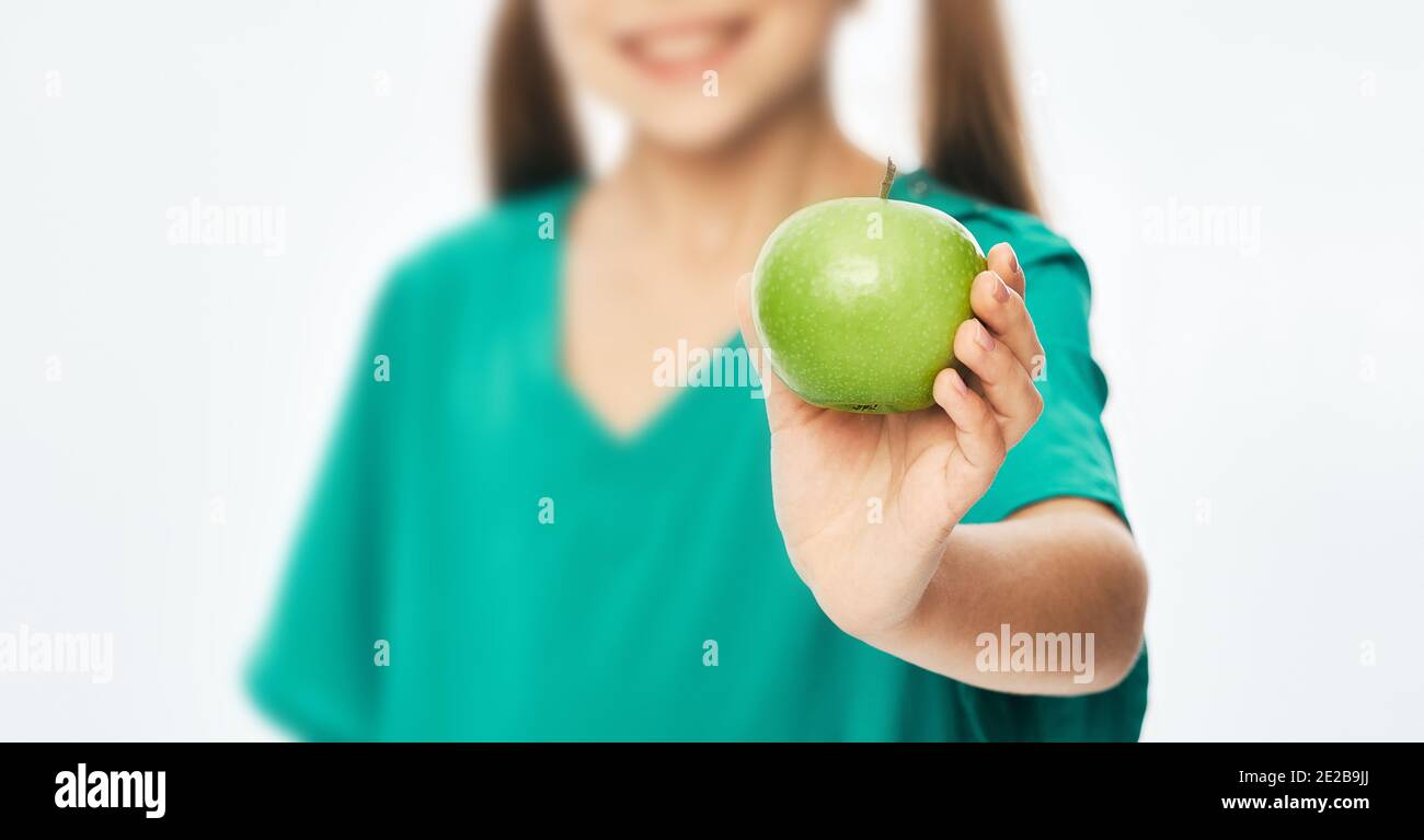 Ein Mädchen, das einen grünen Apfel in der Hand hält. Gesunde und gesunde Nahrung, Früchte in der Ernährung des Kindes Stockfoto