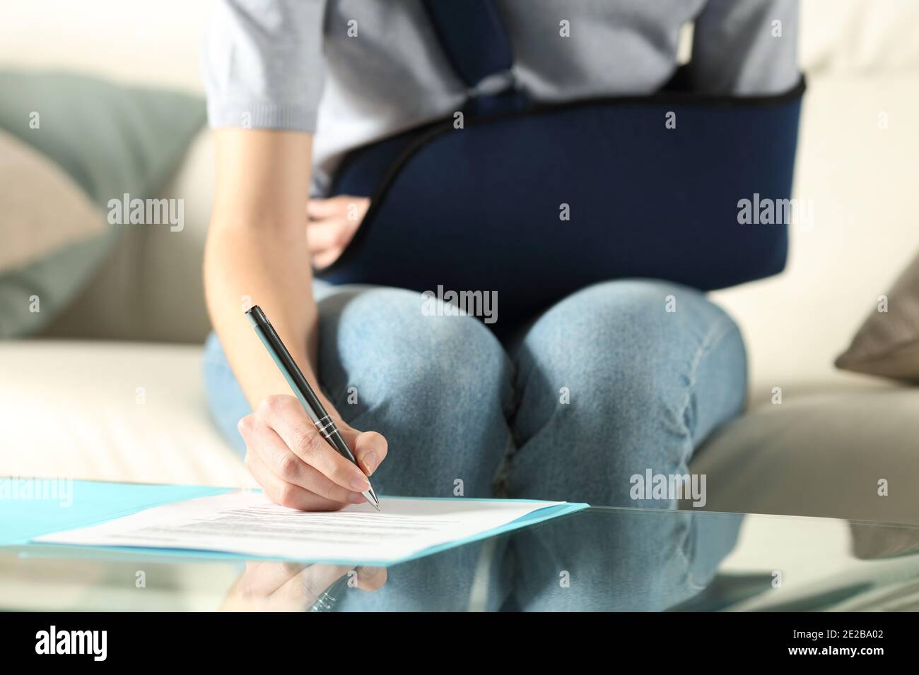 Vorderansicht einer behinderten Frau mit Schlinge bei Vertragsunterzeichnung Zu Hause Stockfoto