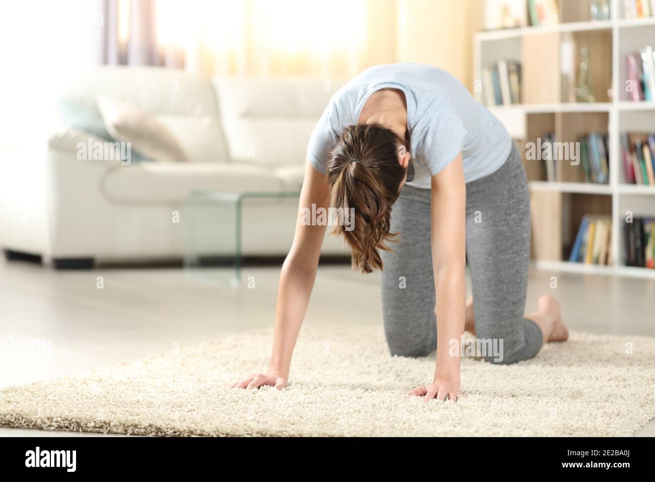 Frau praktiziert Yoga Katze Pose auf dem Boden zu Hause Stockfoto