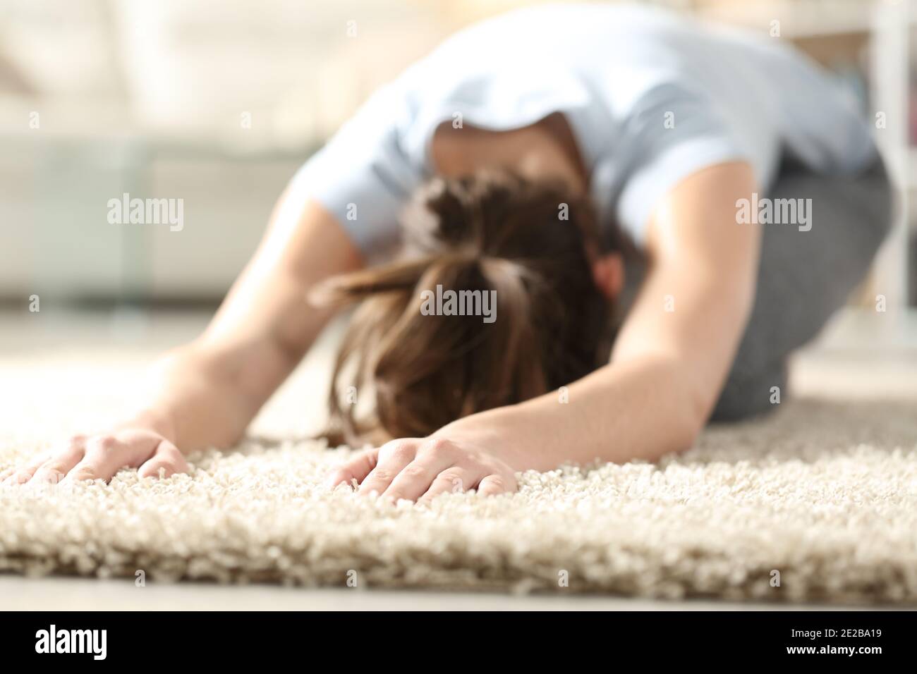 Frau tut Yoga Kind Pose auf einem Teppich in der Wohnzimmer zu Hause Stockfoto