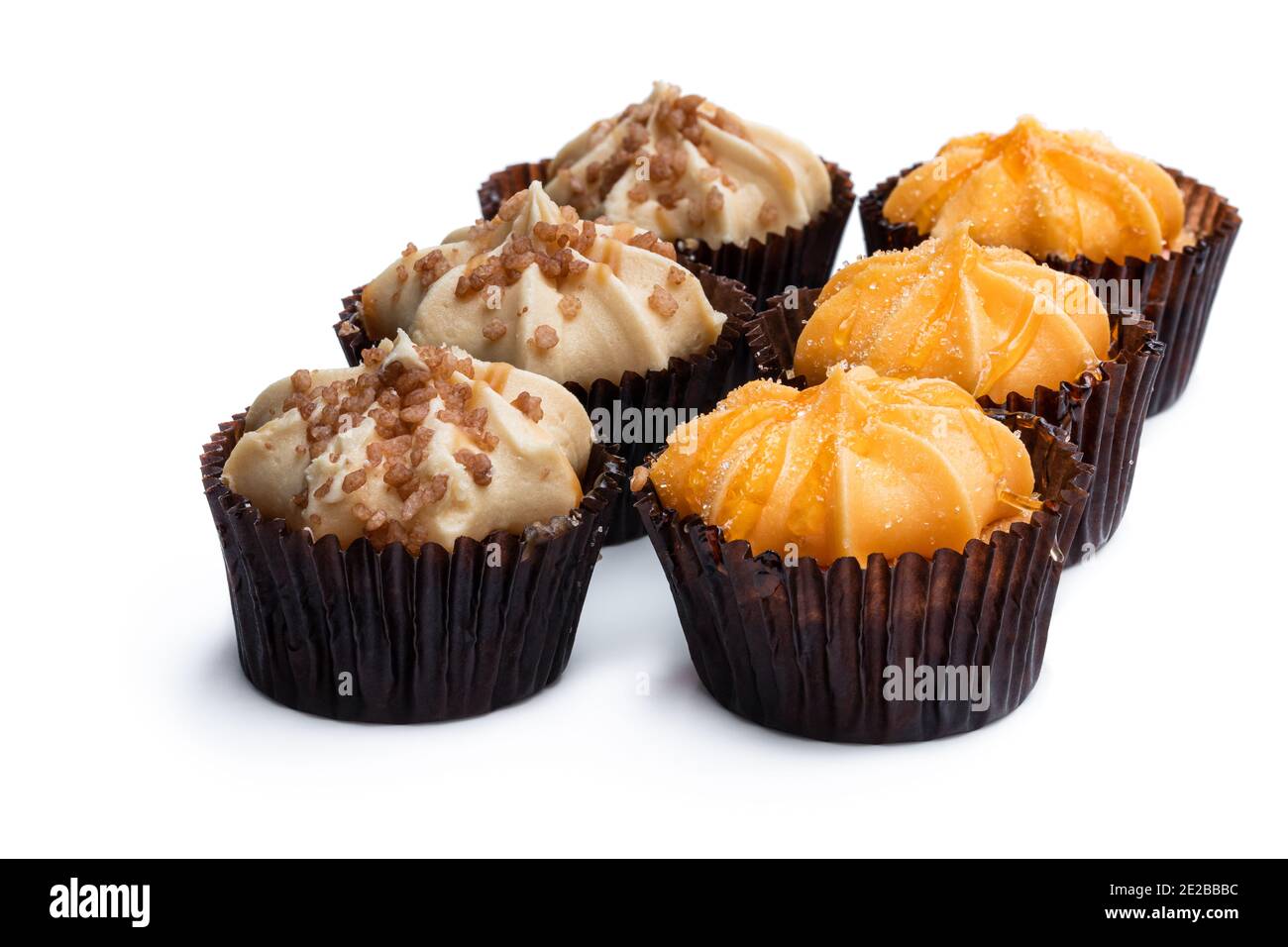 Mini Biskuit Kuchen mit Orange und Karamell Buttercreme garniert isoliert Auf Weiß Stockfoto
