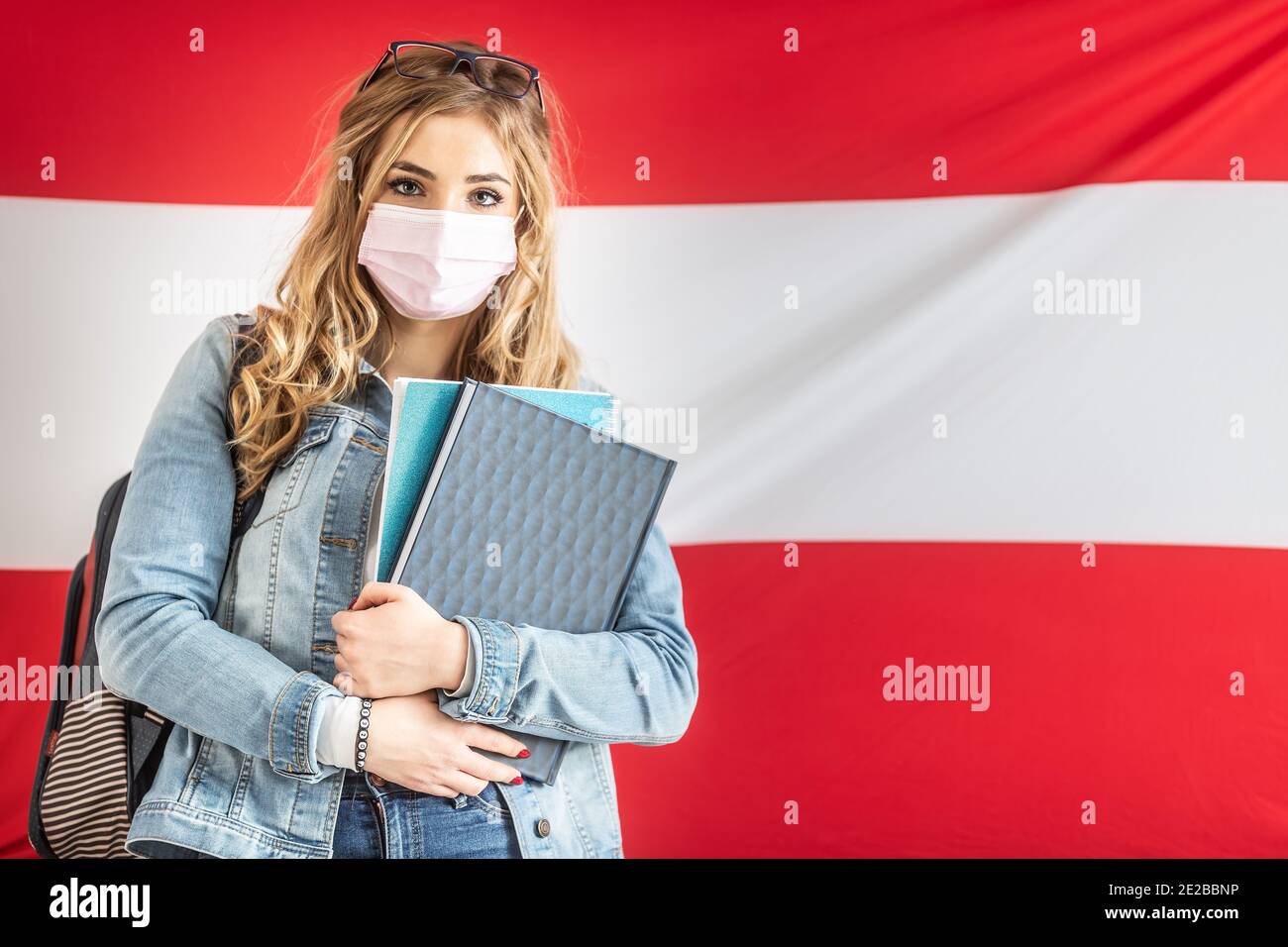 Studentin in Gesichtsmaske steht vor der Flagge von Österreich. Stockfoto