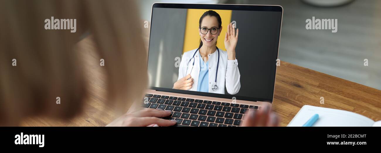 Ärztin auf Laptop-Bildschirm winkt Hand zu kranken Patienten Stockfoto